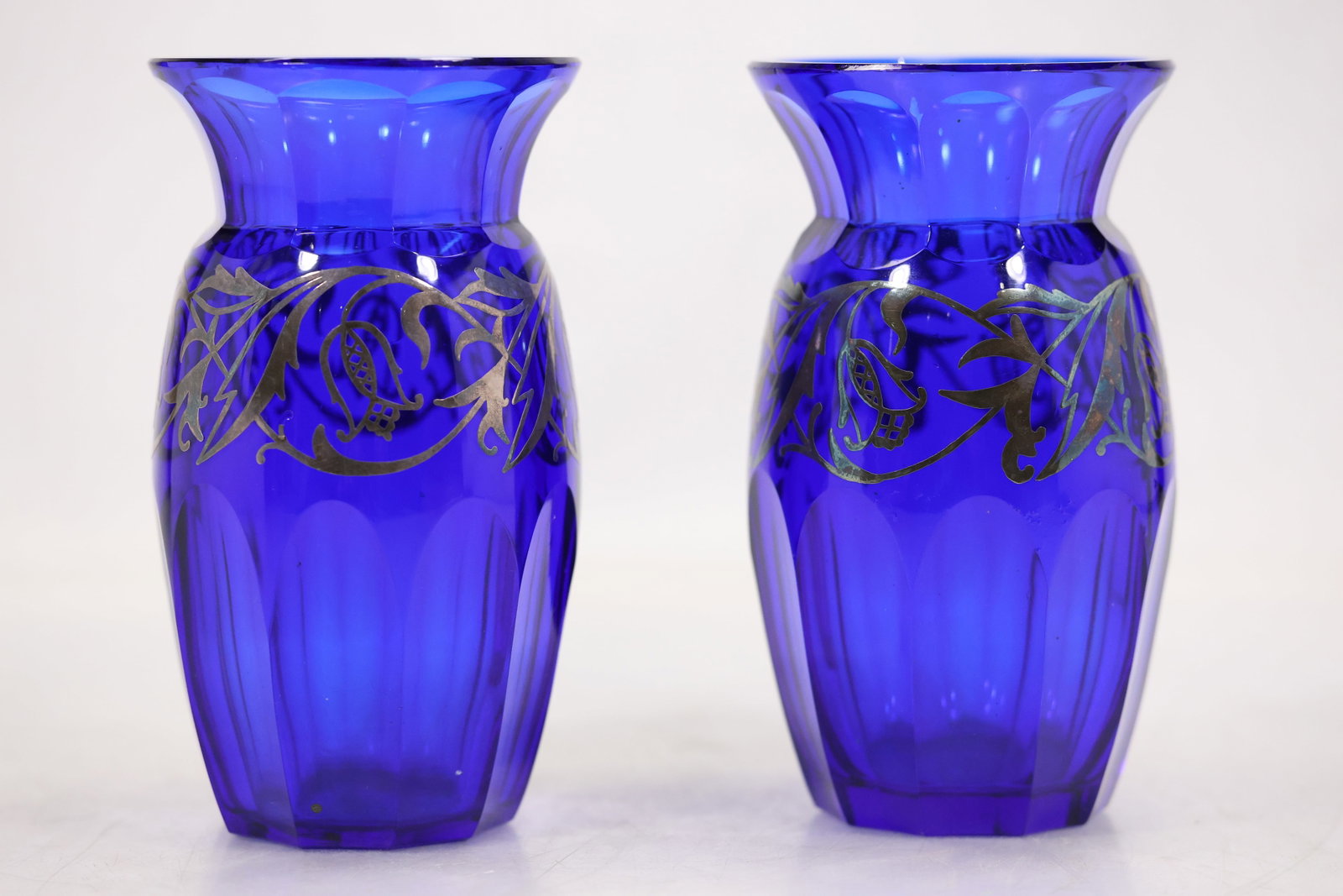 Pair Cobalt Blue Molded Art Glass Vases: A matched pair of cobalt blue art glass vases has molded geometric bodies and narrow openings. Their identical profiles saturated color and repeated surface pattern identify them as a coordinated