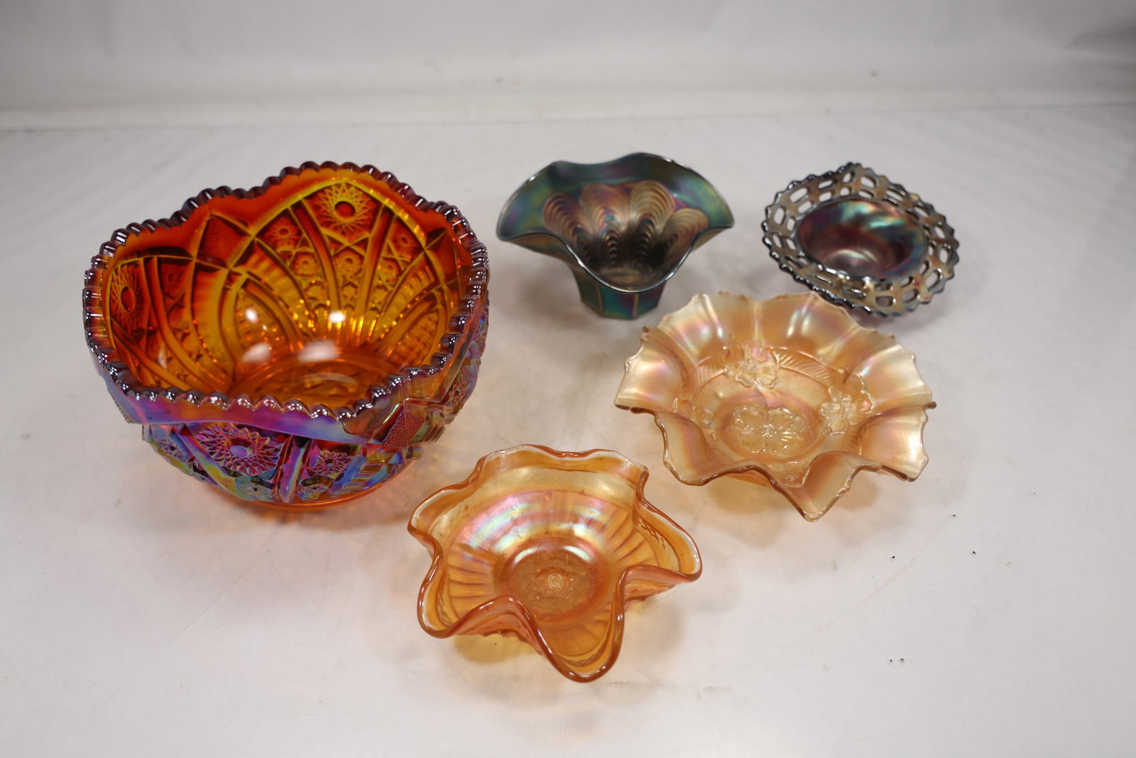 Five Piece Iridescent Art Glass Bowl Group: A group of five art glass bowls combines related iridescent surfaces with varied rounded forms. Reflective color shifts and translucent bodies connect the assembled pieces while no maker is