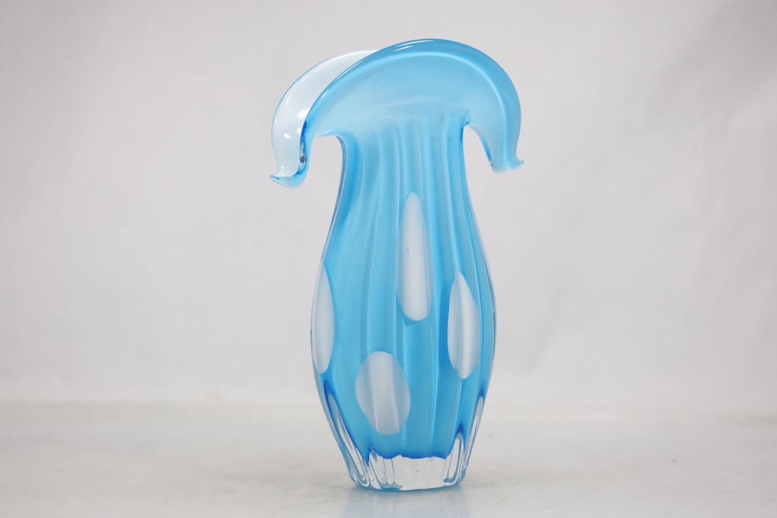 Blue and White Polka Dot Art Glass Vase: An art glass vase has a blue body covered with evenly spaced white polka dot decoration. The rounded hand formed profile and contrasting applied pattern create a playful modern vessel and no maker is