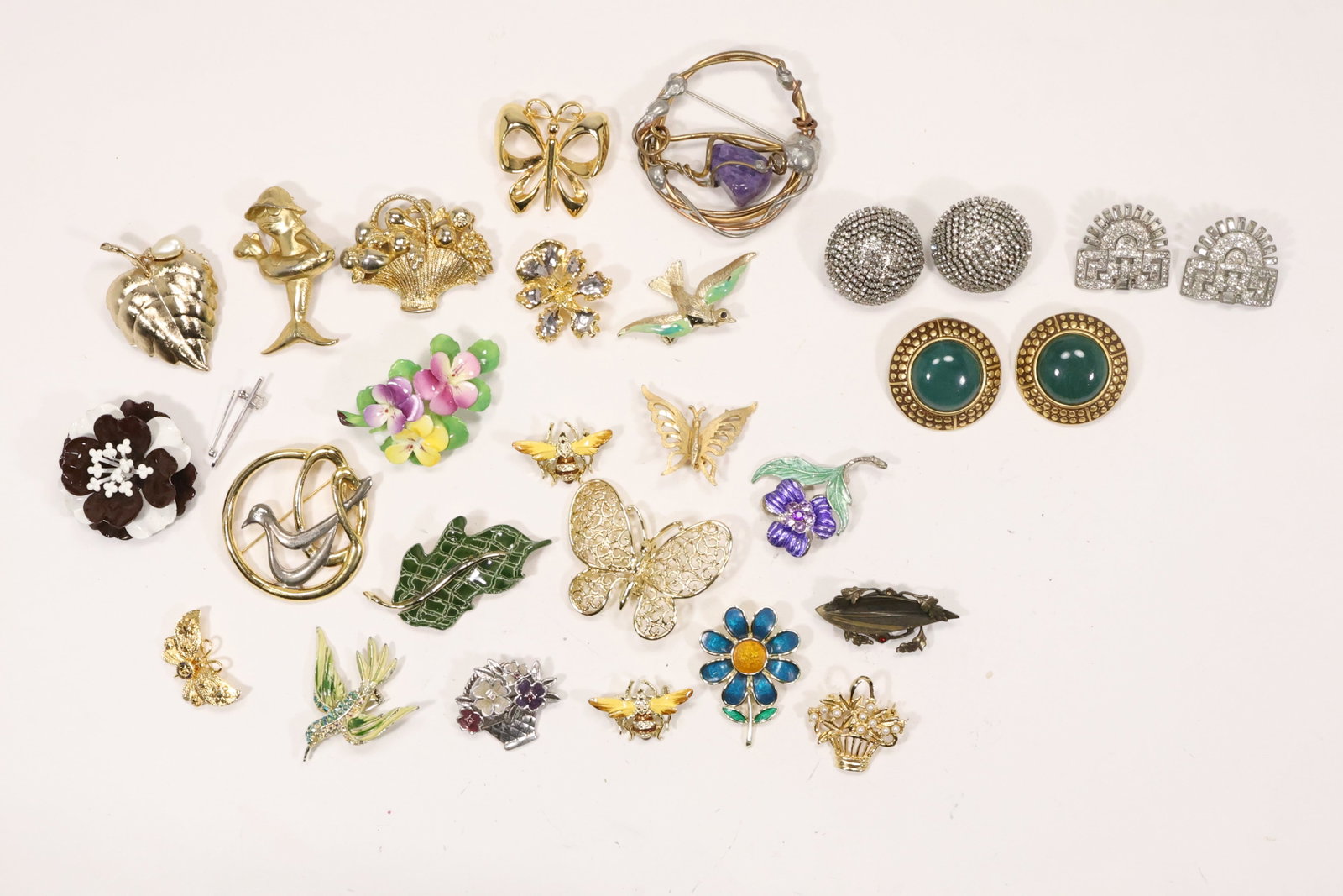Estate Group of Assorted Costume Pins and Earrings: An estate jewelry group contains assorted fashion pins and earrings in gold tone silver tone enamel and stone set designs. The mixed figural floral and geometric motifs represent an assembled costume 