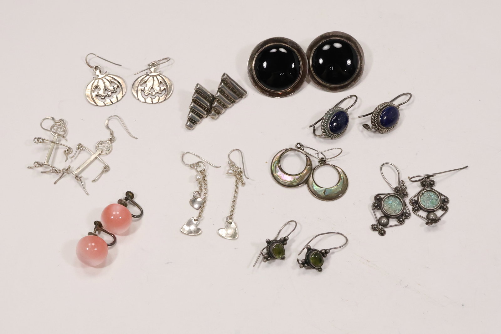 Ten Pairs Sterling Silver Gemstone Earrings: A group of ten pairs of sterling silver pierced and clip earrings includes black onyx lapis peridot abalone and heart form designs. The mixed group combines studs hoops drops and figural forms as show