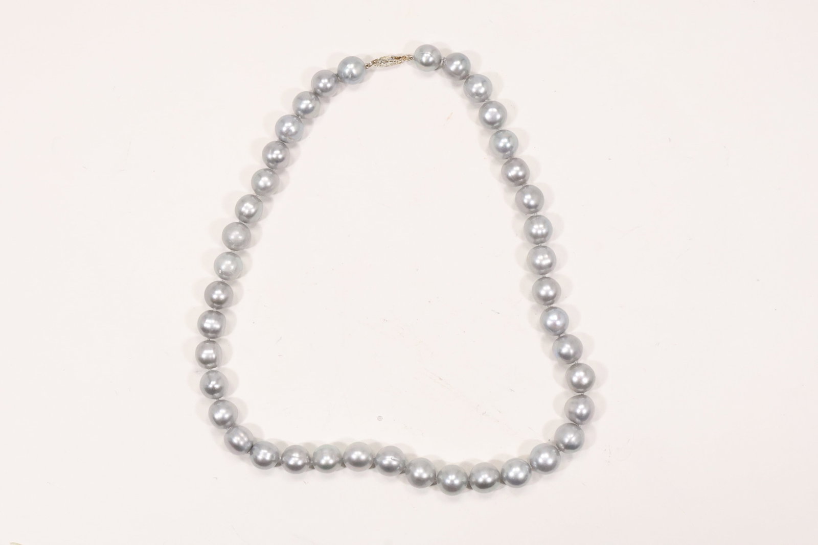 Freshwater Pearl Necklace with Rhodium over Sterling Clasp: A cultured freshwater pearl necklace has graduated silvery gray pearls and a clasp documented as rhodium over .925 sterling silver. The single strand arrangement and luminous bead surfaces are visible