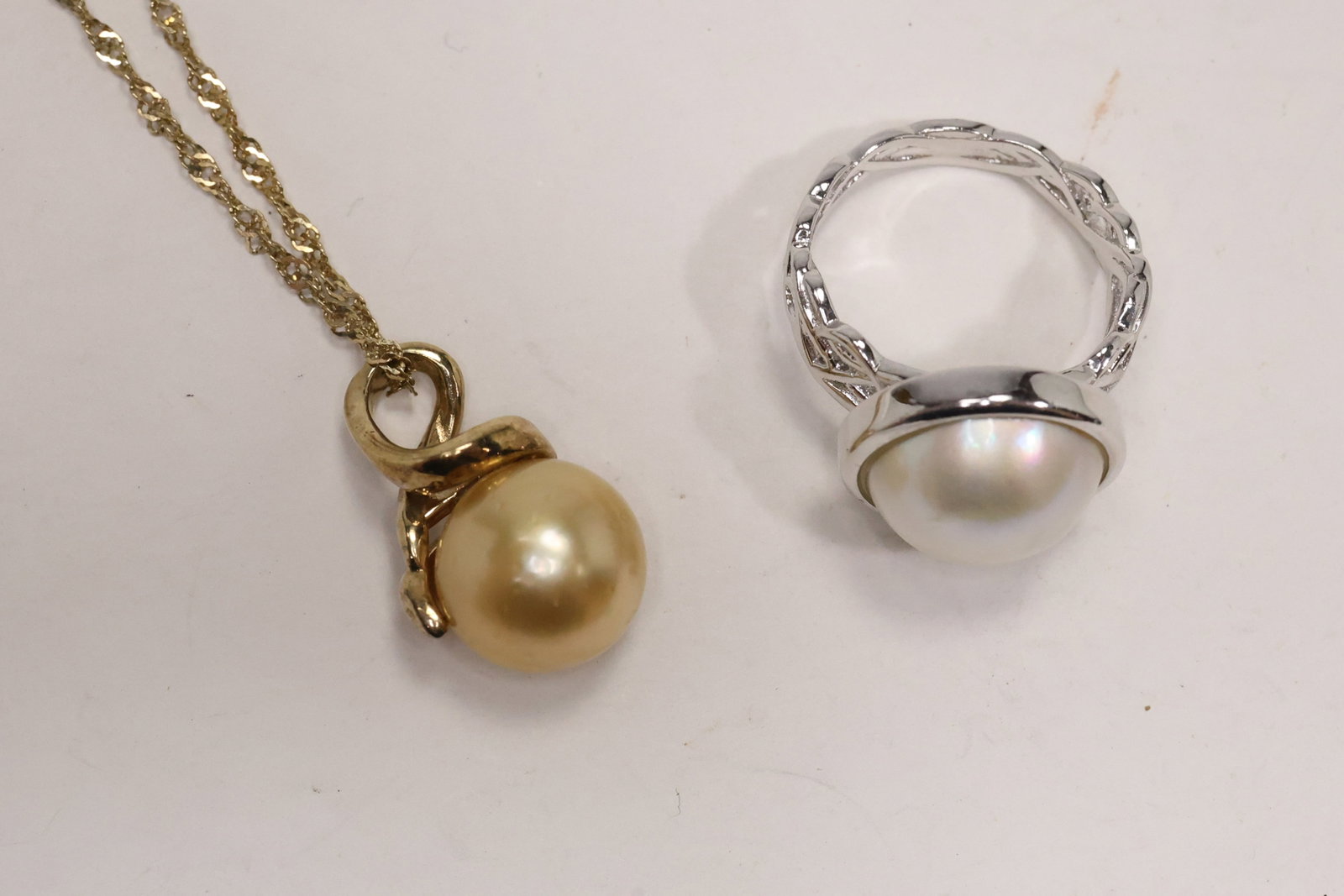 Golden and White Cultured Pearl Sterling Jewelry Group: A two piece jewelry group includes a golden cultured freshwater pearl necklace on a gold vermeil chain and a white cultured South Sea mabe pearl ring with rhodium over sterling setting. The contrastin
