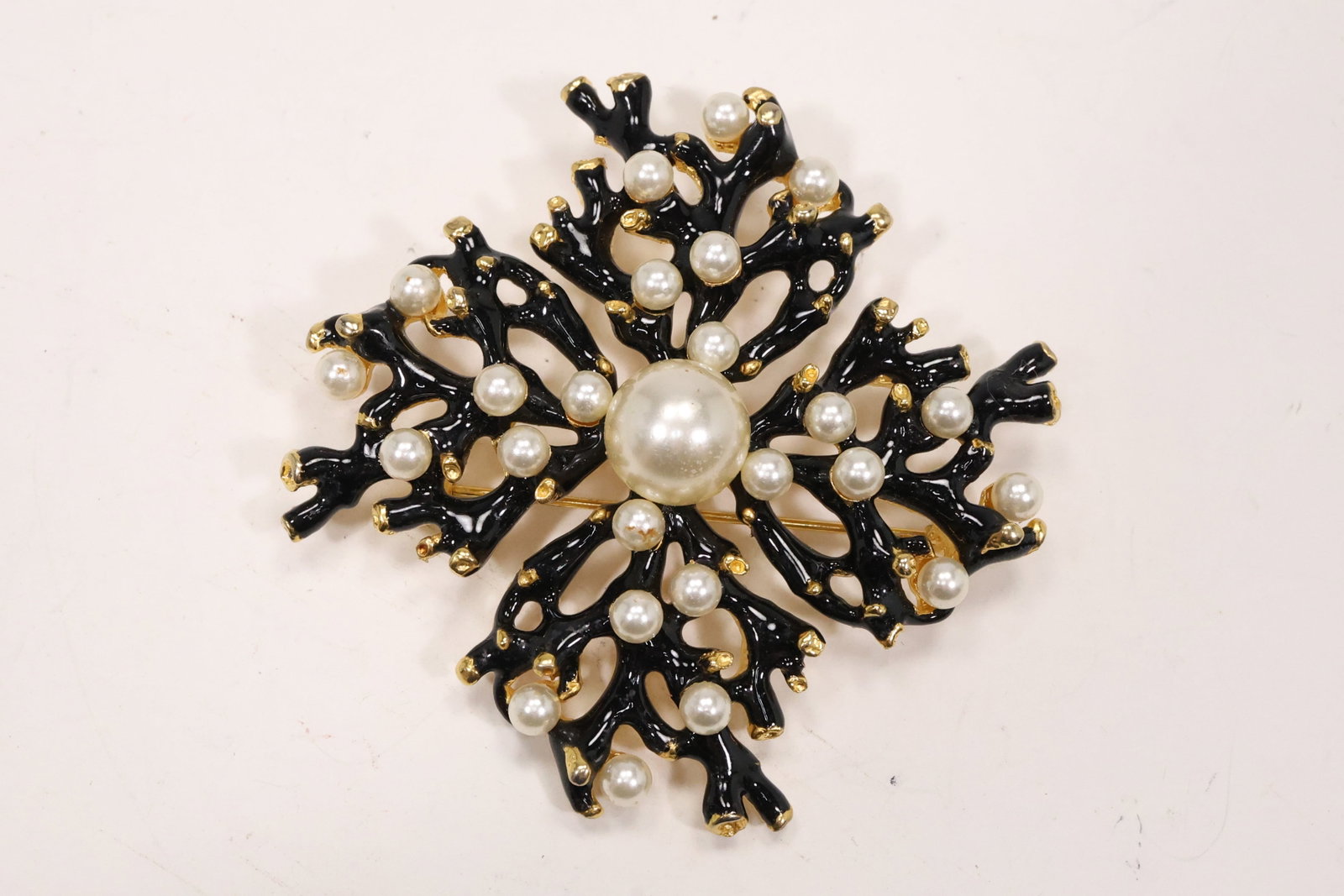 Kenneth Jay Lane Faux Pearl and Black Enamel Pin Pendant: A Kenneth Jay Lane gold tone pin and pendant has a large circular form with faux pearl clusters and black enamel accents. The maker identification follows the original catalog notes and the