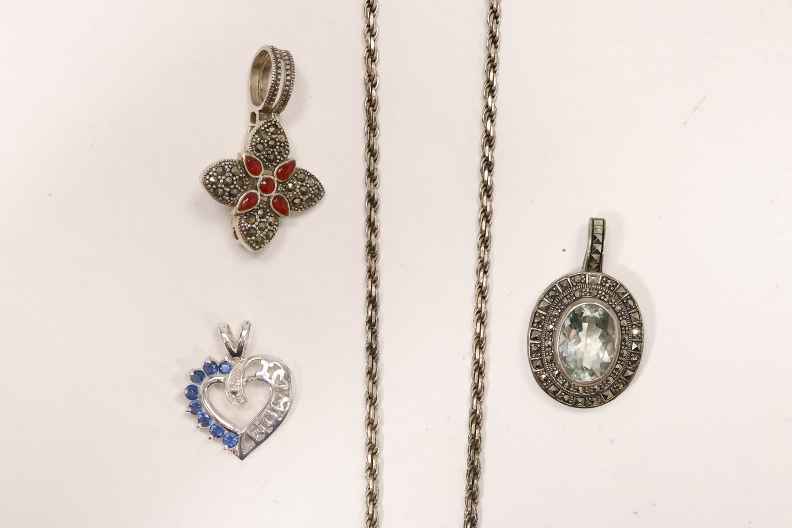 Sterling Silver Necklace with Three Gemstone Pendants: A sterling silver group includes a rope twist chain and three pendants set with blue amethyst red enamel marcasites and blue stones. The heart oval and rectangular forms create a varied coordinated