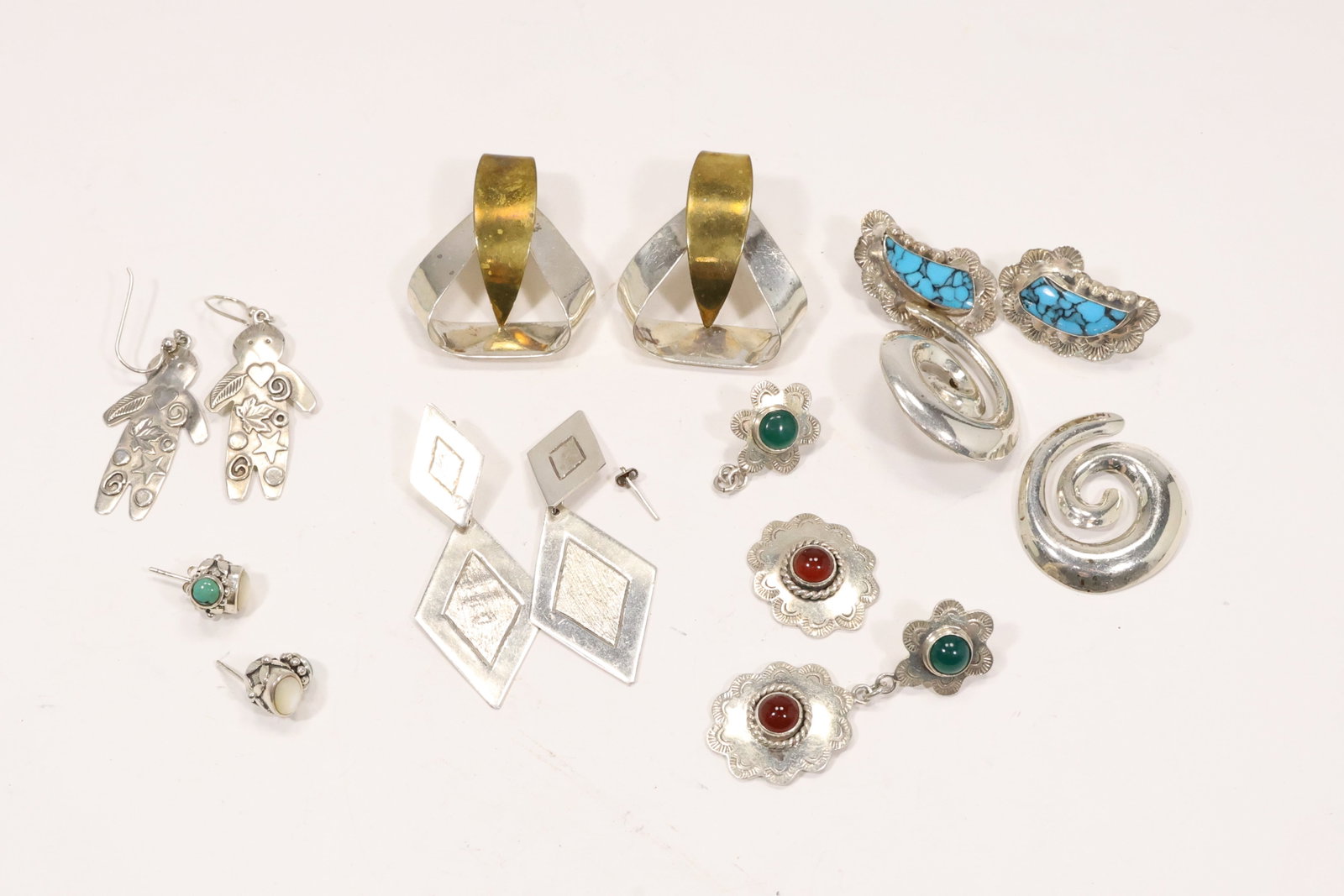 Seven Pairs Mexican Sterling Silver Gemstone Earrings: A seven pair sterling silver earring group includes Mexican modernist geometric designs with brass opal turquoise jade carnelian and figural motifs. Maker and workshop codes are retained in the