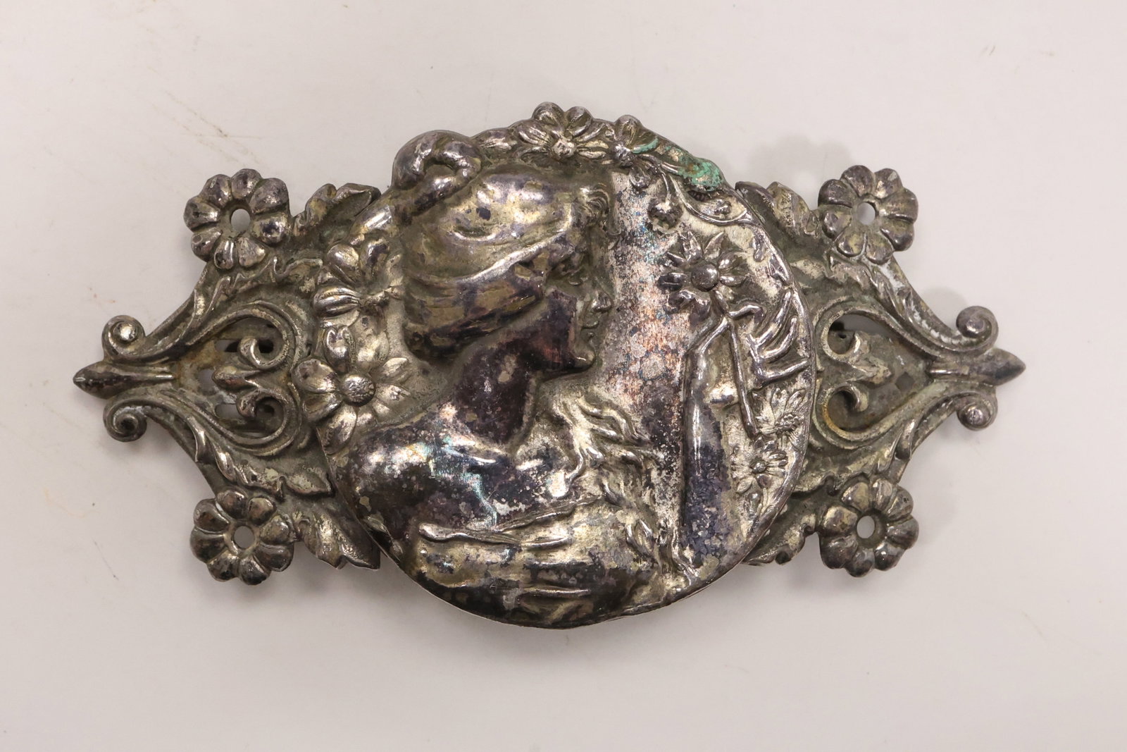 Victorian Style Ornate Sterling Silver Figural Barrette: An ornate sterling silver barrette has a wide openwork plaque with scrolling foliate decoration and a central classical figural medallion. The reverse carries a long barrette mechanism and no maker