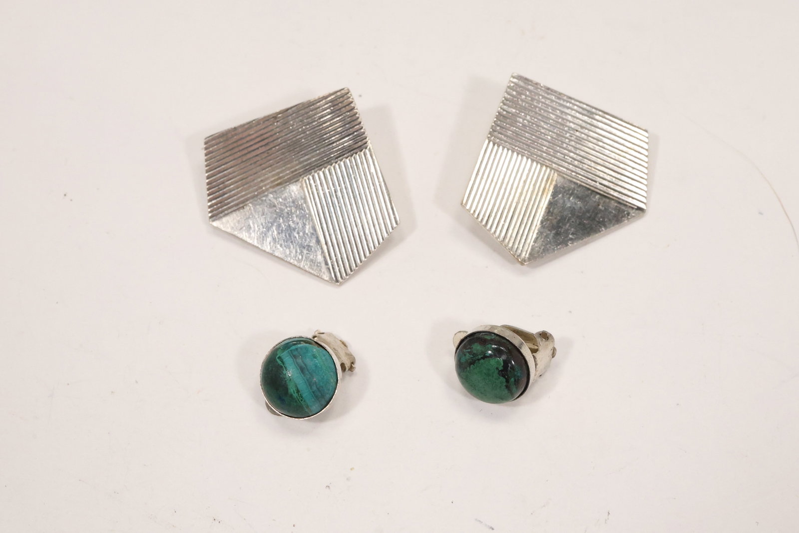 Mexican Sterling Modernist and Malachite Clip Earrings: A two pair earring group includes Mexico marked .925 triangular modernist clips and round sterling clips set with green malachite cabochons. The geometric forms and stone settings are visible in the
