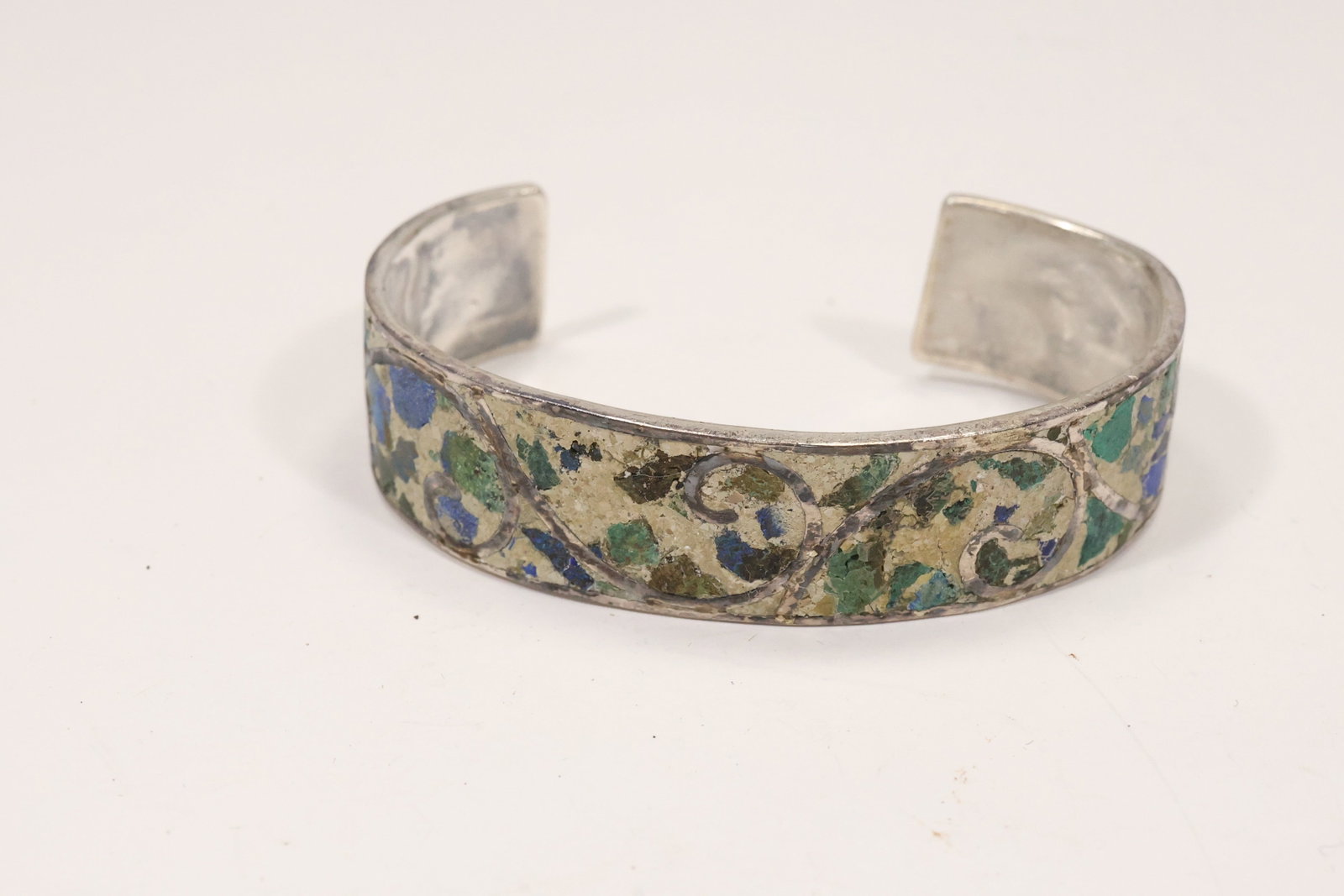 Mexican Sterling Lapis and Malachite Inlay Cuff Bracelet: A Mexico marked sterling silver cuff bracelet has a wide band decorated with lapis and malachite inlay arranged in geometric panels. The open cuff format and multicolor stone work support a modernist