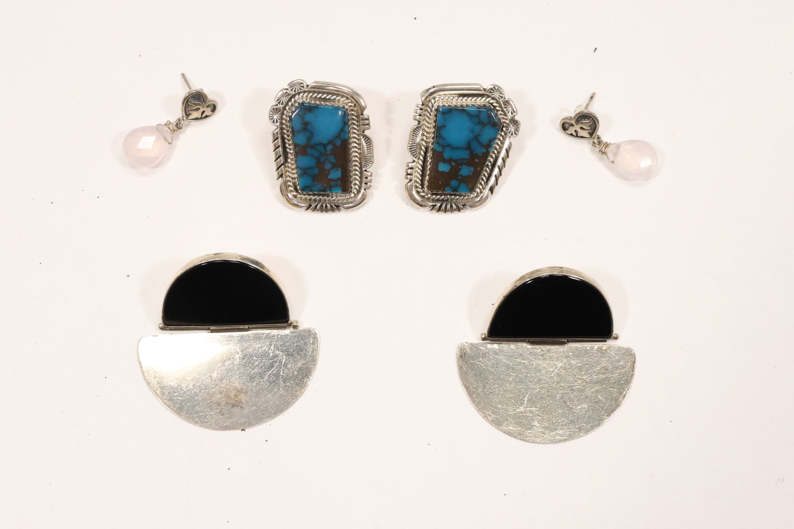 Sterling Silver Turquoise Onyx and Rose Quartz Earrings: A three pair sterling silver earring group includes round turquoise set earrings modernist black onyx earrings and rose quartz drop earrings. The mixed stones and pierced formats form a coordinated es