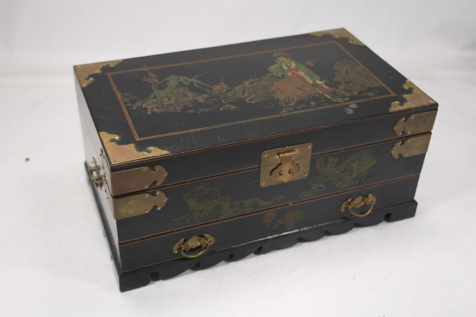 Asian Style Wood Jewelry Chest with Red Interior: A rectangular wood jewelry chest has carved or painted Asian style exterior panels brass tone hardware lift top and a fitted red interior with small compartments and drawer. No maker is confirmed. The
