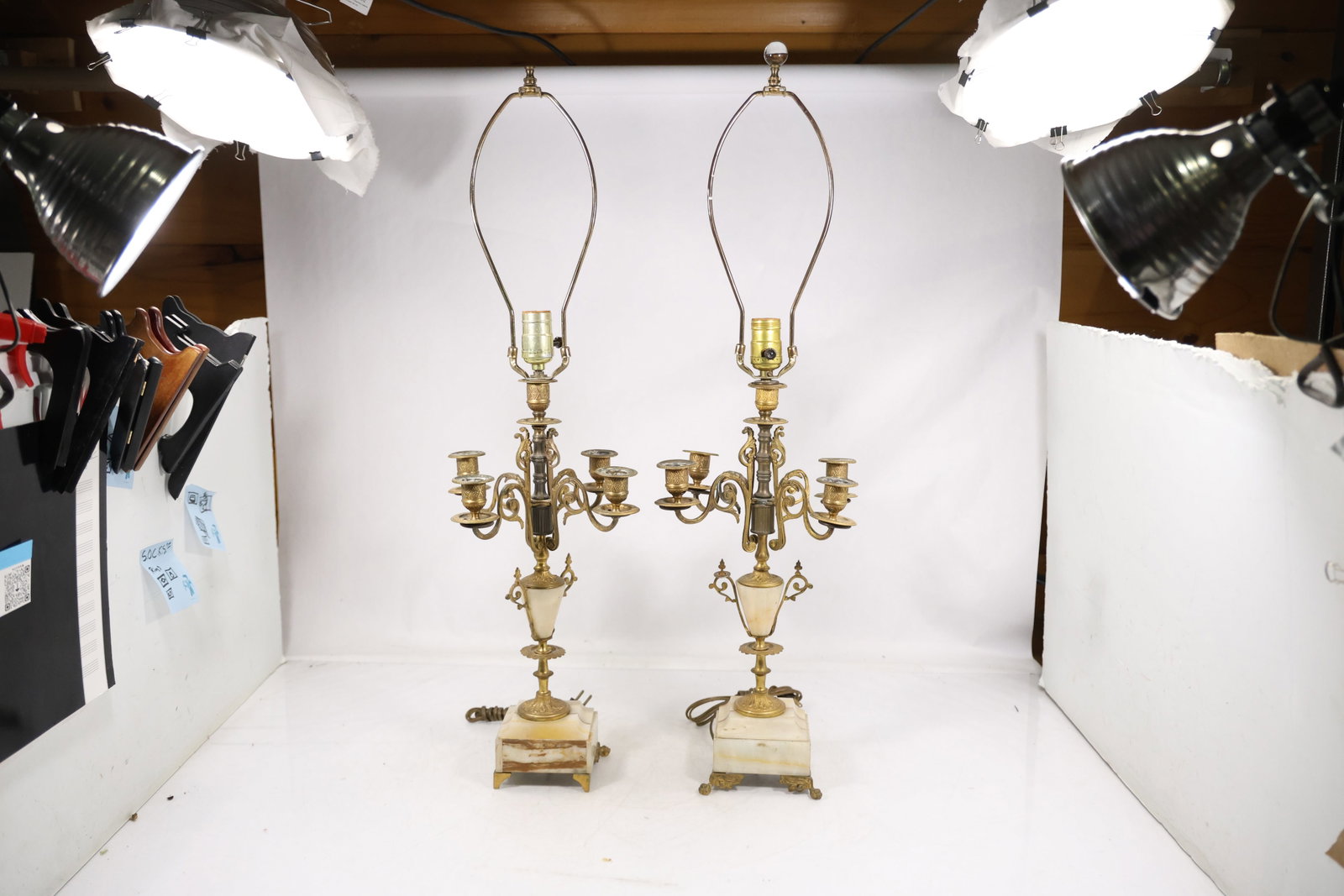 Pair Brass Three Light Electric Candelabrum Lamps: A matched pair of brass table lamps is formed as three light candelabra with scrolling arms tall central standards decorative bobeches and electrical candle sockets. No maker is confirmed. The decorat