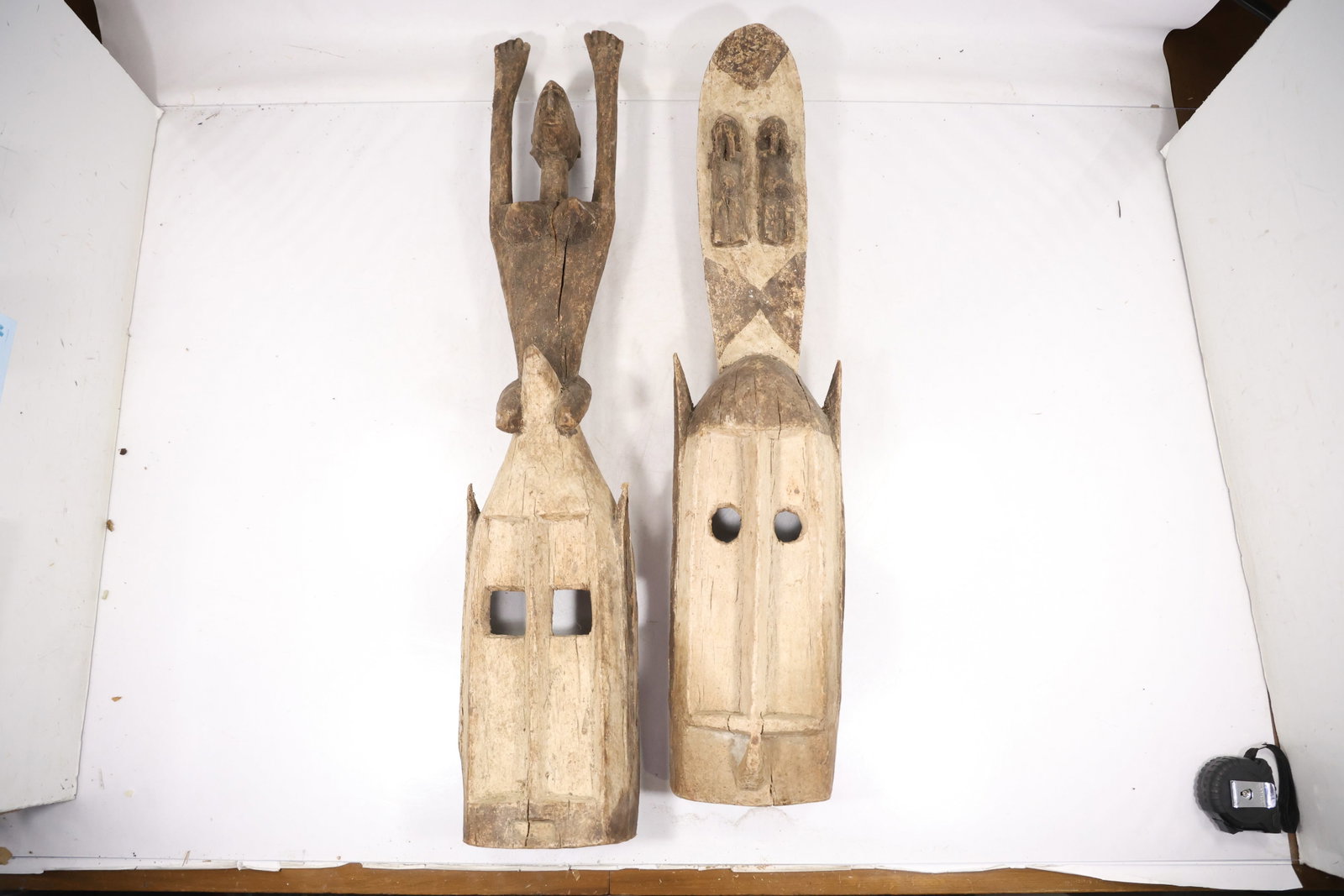 Pair Tall Carved Wood Tiki Figure Sculptures: A pair of tall carved wood figures has elongated bodies mask like faces and incised geometric decoration. The matched vertical forms support a Polynesian tiki style description without a specific cult