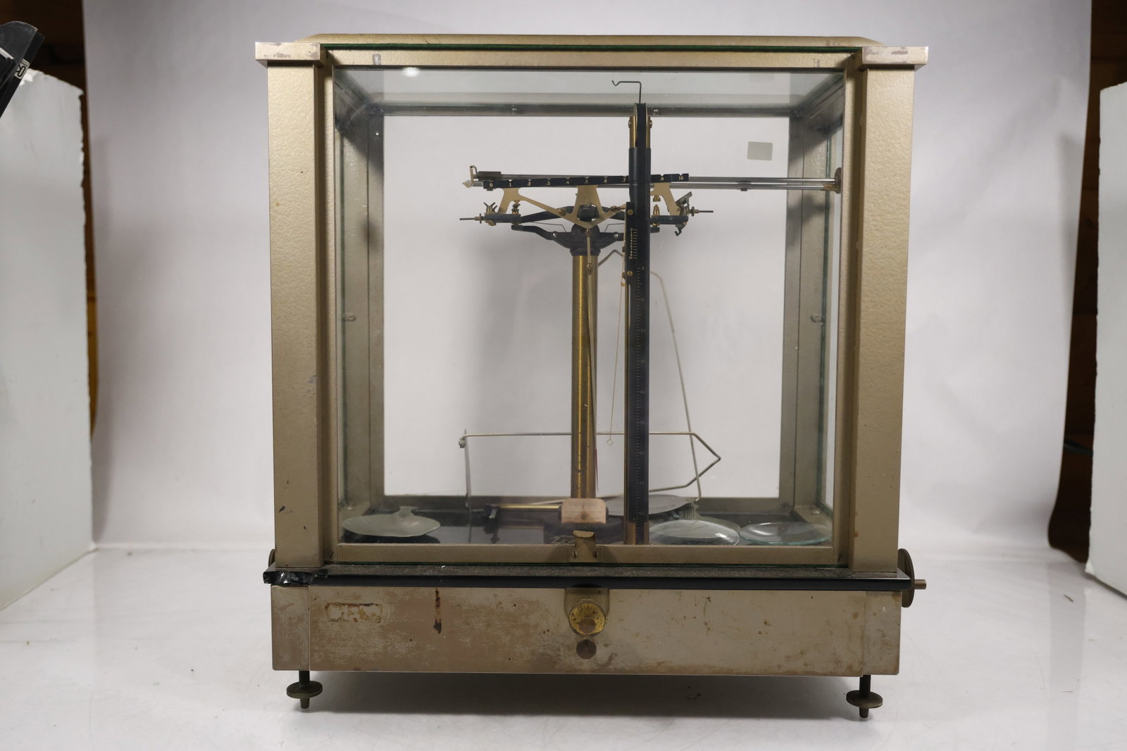 Vintage Analytical Balance Scale in Glass Display Case: A laboratory analytical balance is enclosed in a rectangular glass sided wood and metal case with central beam pans and adjustment controls. The protective cabinet and precision weighing mechanism