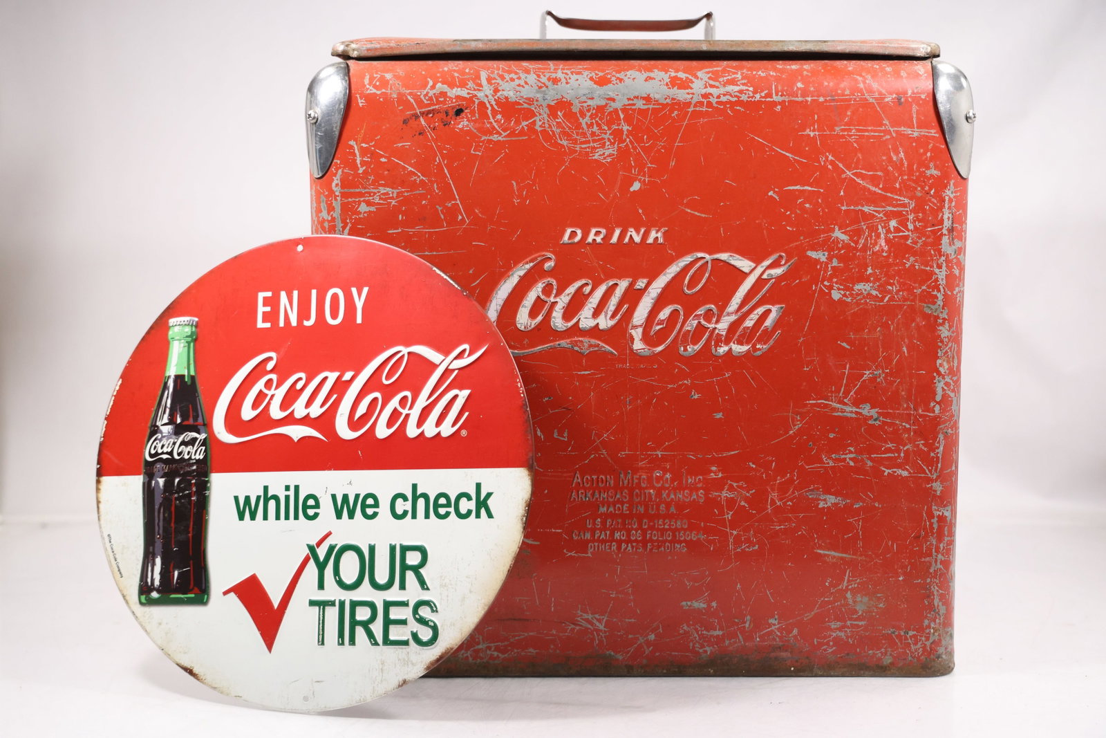 Vintage Coca Cola Red Metal Picnic Cooler: A red metal Coca Cola cooler has a rectangular carrying case with handle and period advertising graphics including a tire themed slogan panel. The printed Coca Cola branding and portable insulated for
