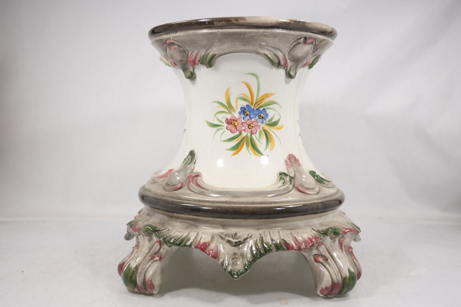 Floral Porcelain and Brass Mounted Cachepot Planter: A porcelain cachepot or planter has painted floral decoration a flared rim and an ornate brass tone mounted base with scroll feet. The mixed ceramic and metal construction creates a formal decorative