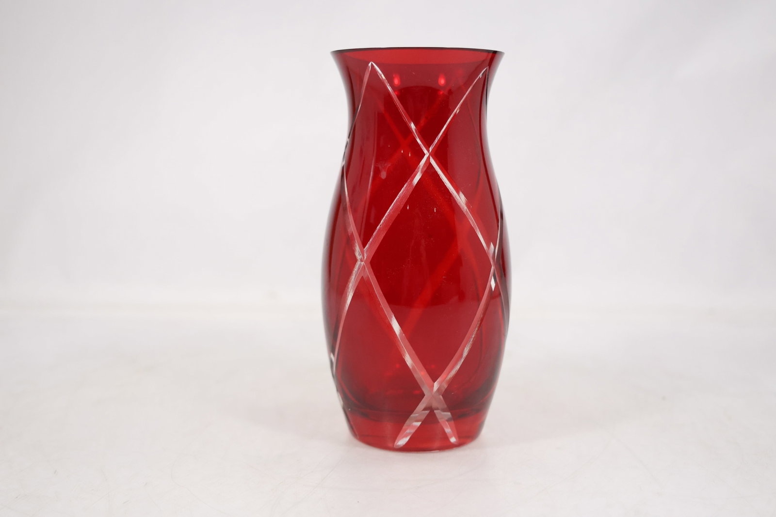 Ruby Red Diamond Pattern Art Glass Vase: A ruby red glass vase has a tapered cylindrical body flared rim and an applied or cut diamond lattice pattern around the exterior. The saturated color and geometric surface support an art glass identi