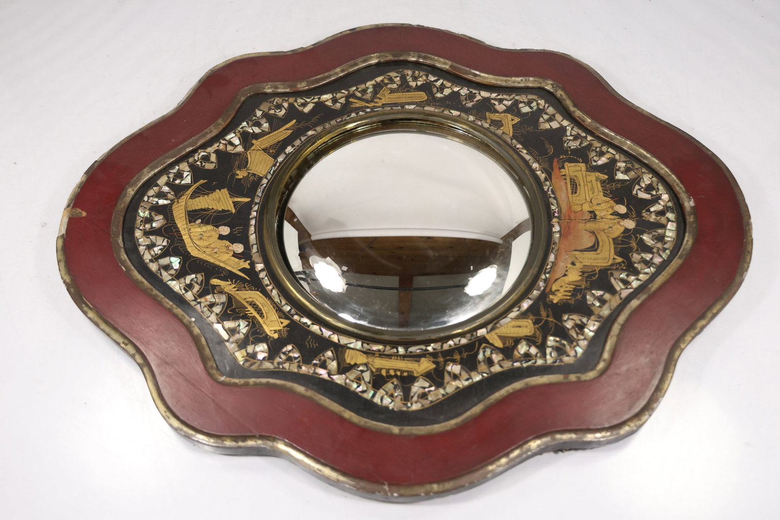 Large Ornate Venetian Style Handled Wall Mirror: A large decorative mirror has an ornate shaped frame with red green and gold tone patterned decoration and an extended wood handle or lower support. The elaborate profile supports a Venetian style