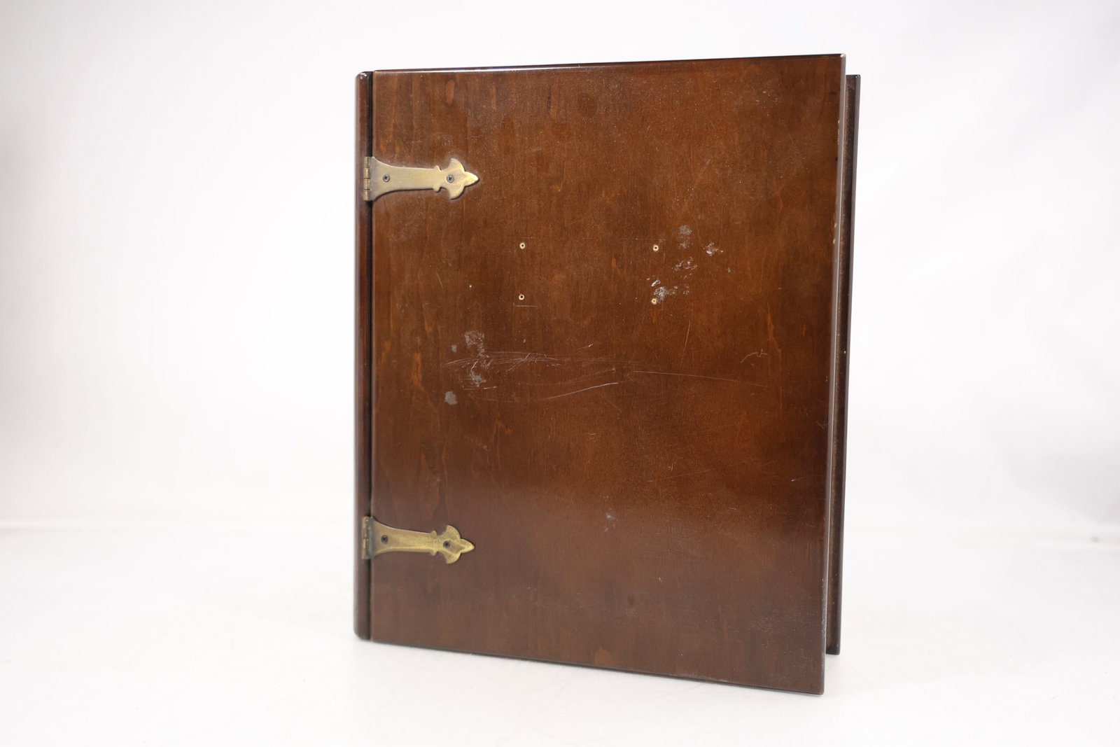 Hinged Wood Book Form Display Cabinet: Wood display cabinet constructed in the form of an oversized hinged book with brass tone strap hinges. The case opens to reveal a fitted interior compartment and shelves with visible wood grain