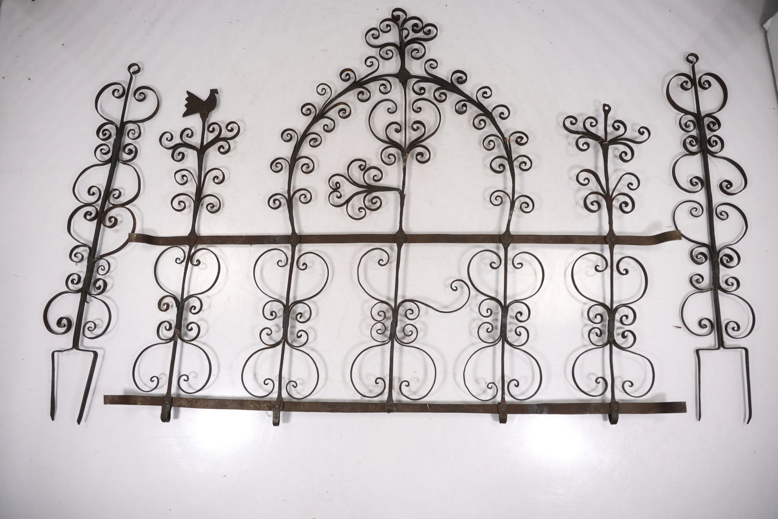 Pair Black Wrought Iron Garden Fence Panels: Pair of decorative wrought iron fence or garden gate panels with scrolling vine forms leaf terminals and arched upper profiles. The openwork metal construction creates a symmetrical architectural