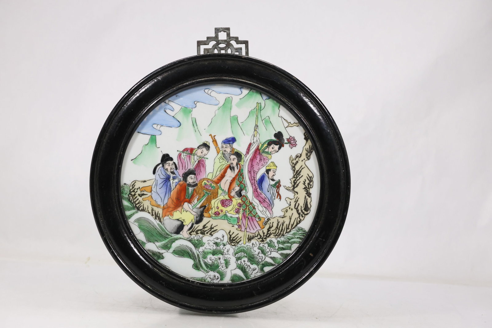 Japanese Painted Figural Wall Plaque: Round Japanese decorative plaque with colorful painted figures landscape details and floral motifs set within a dark square display frame. The dense narrative composition uses bright enamel like
