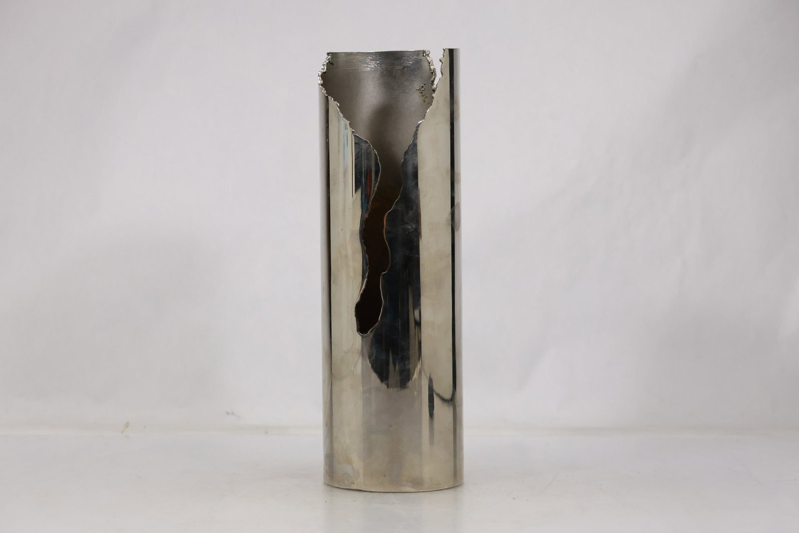 Modernist Stainless Steel Abstract Sculpture: Vertical modernist sculpture formed from polished and brushed steel with folded planes and narrow openings. The reflective metal surfaces shift across the angular abstract composition. The work relate