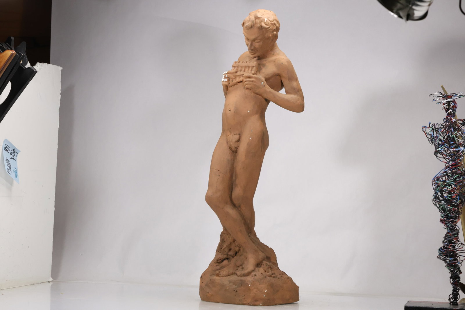Hand Modeled Terracotta Female Figure Sculpture: Tall hand modeled terracotta figure of a standing woman with simplified facial features and textured drapery. The warm clay body and elongated proportions emphasize a studio sculpture aesthetic. The