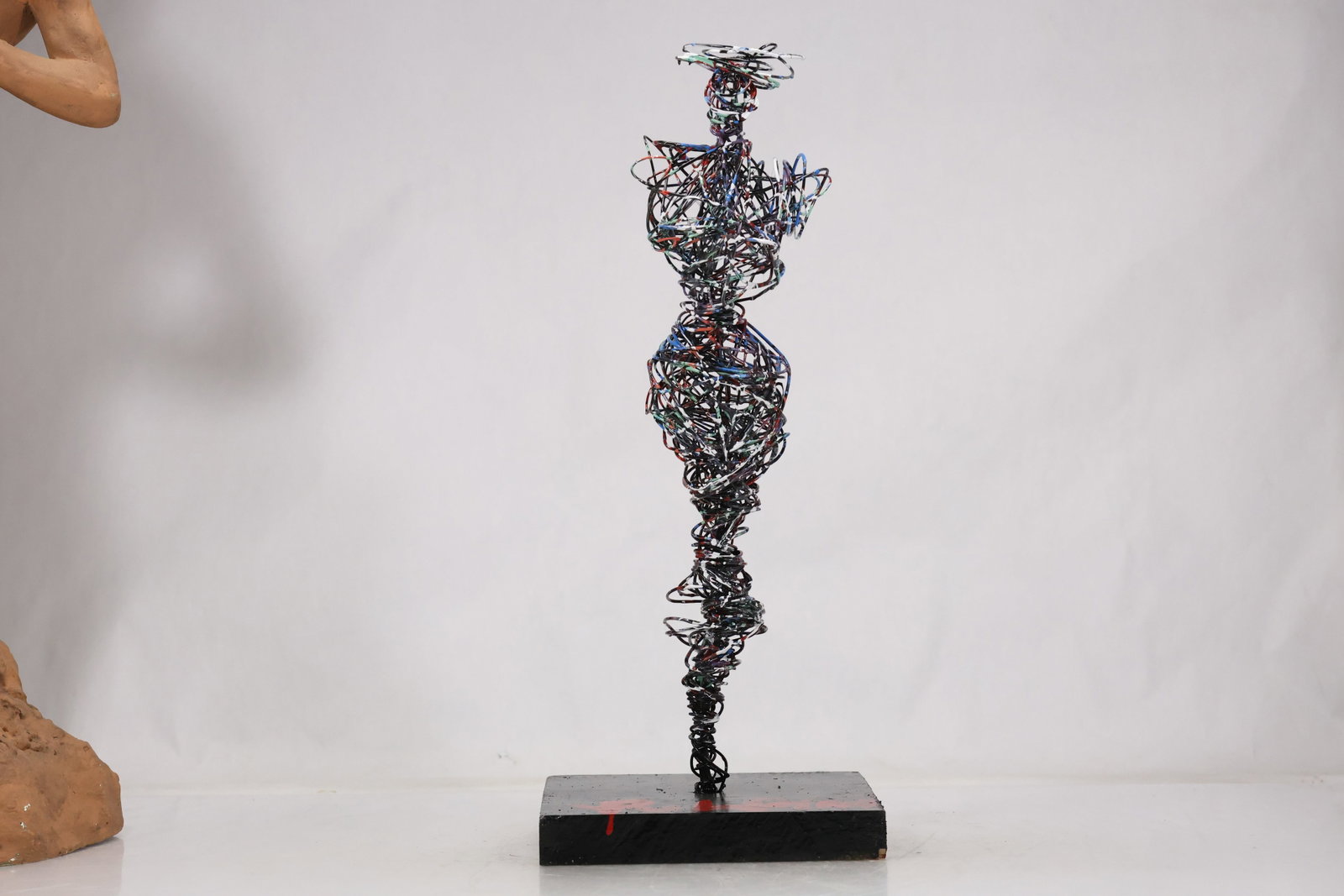 Signed Metal Wire Figural Sculpture: Tall openwork metal sculpture composed of twisted wire and cast details in a vertical figural arrangement. A black base bears a red artist signature visible in the photographs. The work relates to