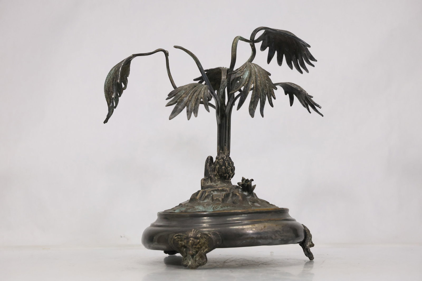 Cast Metal Tree and Wildlife Sculpture: Detailed cast metal sculpture of a branching tree with small birds and woodland figures arranged around a textured circular base. The dark patinated surface emphasizes the layered naturalistic