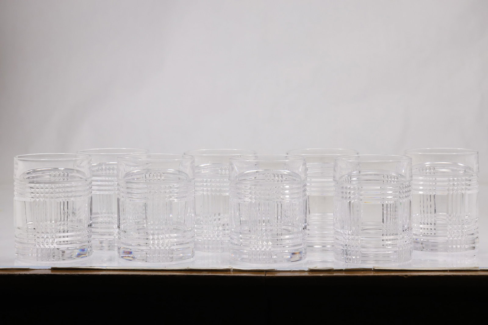 Set of Eight Cut Crystal Tumblers: Set of eight clear crystal tumblers with heavy circular bases and repeating cut geometric decoration. The matching glasses have straight sides and a substantial barware profile. The form relates to