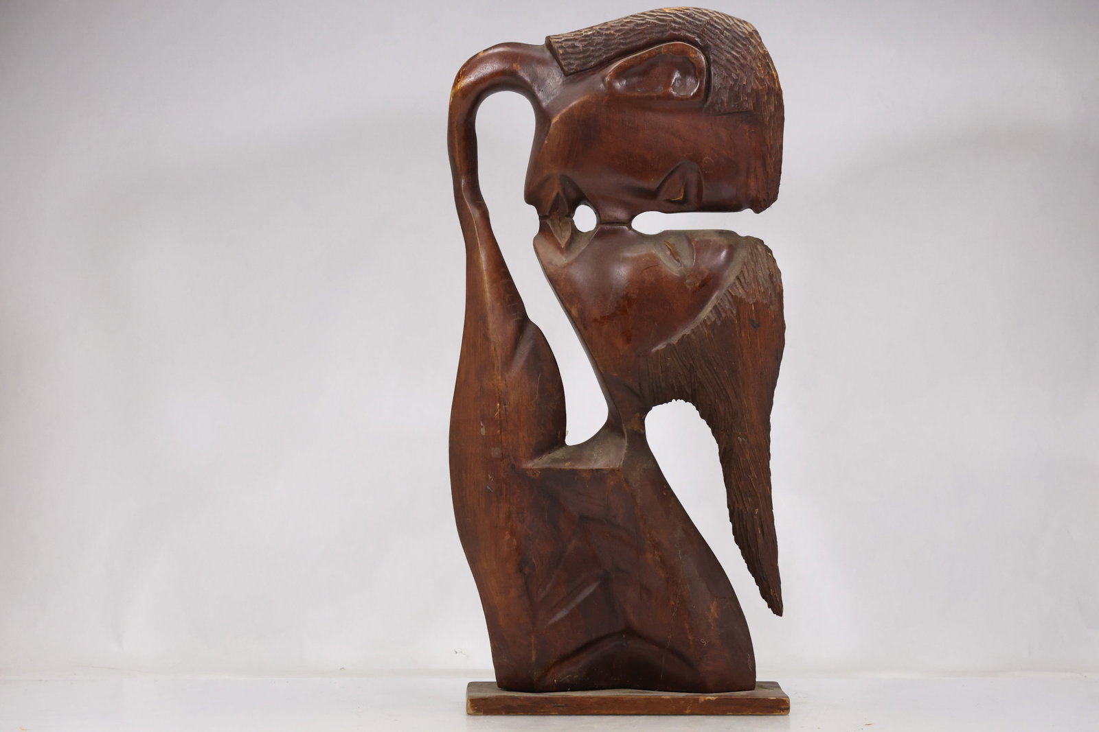 Carved Wood Abstract Family Sculpture: Tall carved wood sculpture with intertwined rounded figures and open negative spaces. The warm dark wood grain and simplified forms suggest an abstract family or embracing group. The design relates