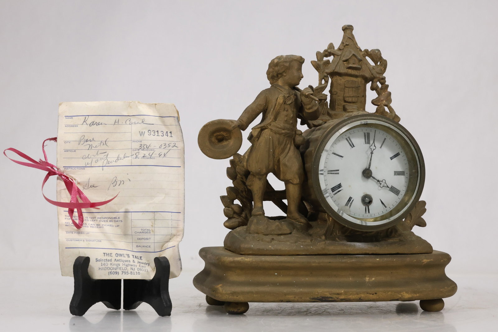 Figural Brass and Stone Mantel Clock: Decorative mantel clock with circular dial set beside a seated classical figure on a dark stone base. Brass tone mounts and sculptural ornament create a nineteenth century revival appearance. The