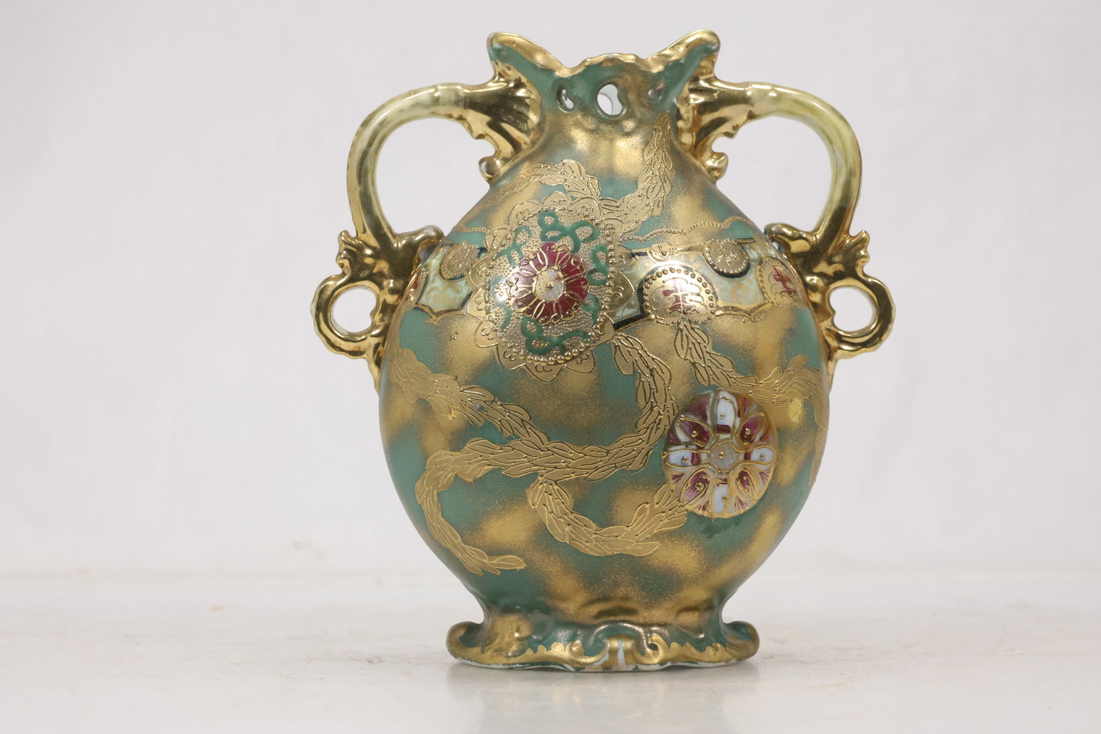 Signed Iridescent Art Glass Vase: Rounded art glass vase with iridescent multicolor surface scrolling applied handles and gold tone accents. The underside bears a blue hand written signature or maker notation. The form relates to