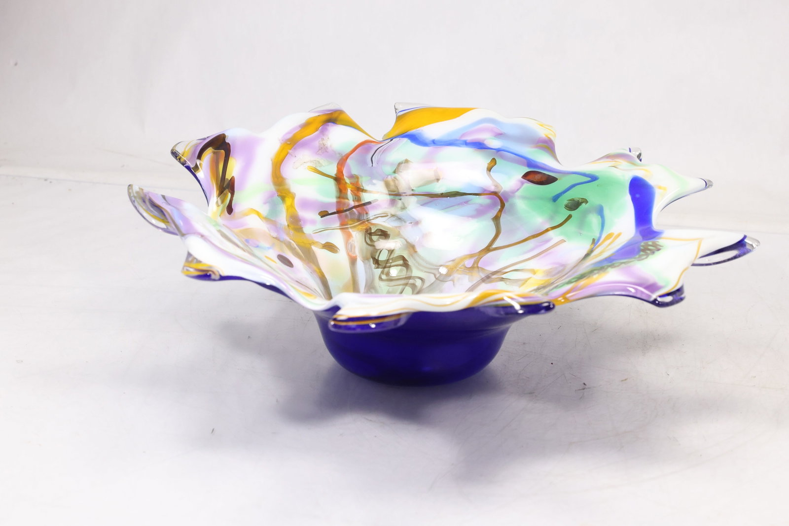 Large Multicolor Freeform Art Glass Bowl: Large freeform art glass centerpiece bowl with folded petal like rim and layered blue yellow pink and clear color. The thick sculptural glass creates an abstract floral form. The form relates to twent