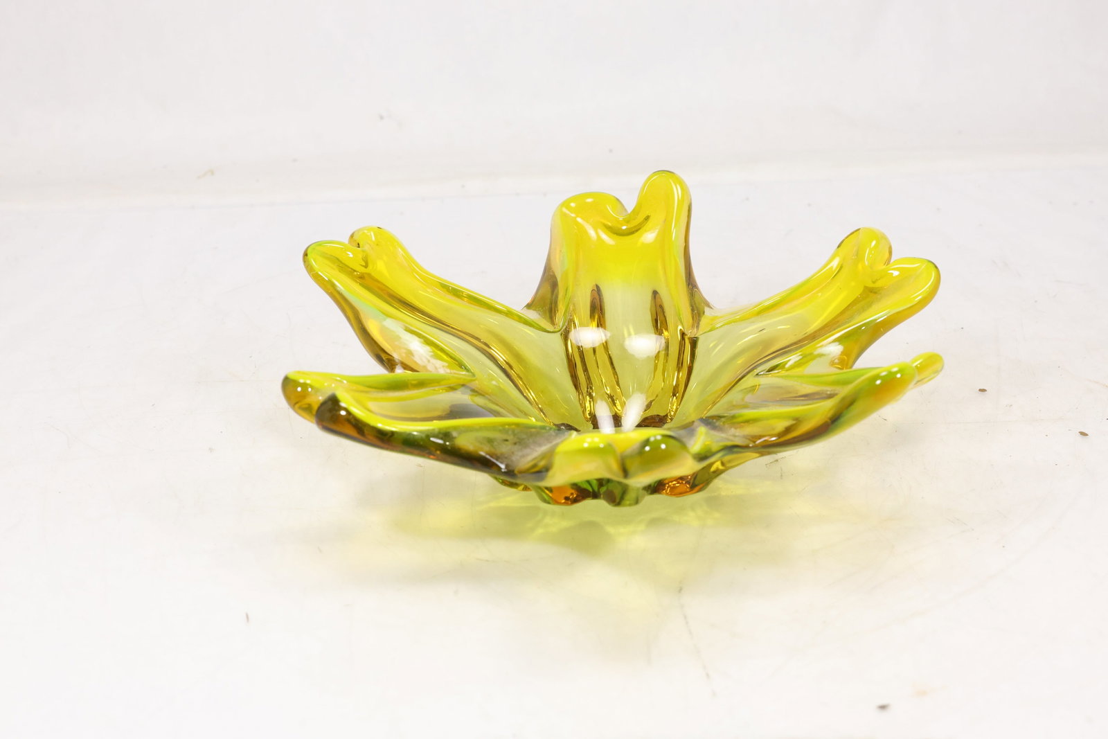 Yellow Freeform Art Glass Centerpiece Bowl: Bright yellow art glass bowl with freeform folded rim and petal like points. The shallow sculptural vessel uses thick transparent glass to create a modern centerpiece form. The form relates to