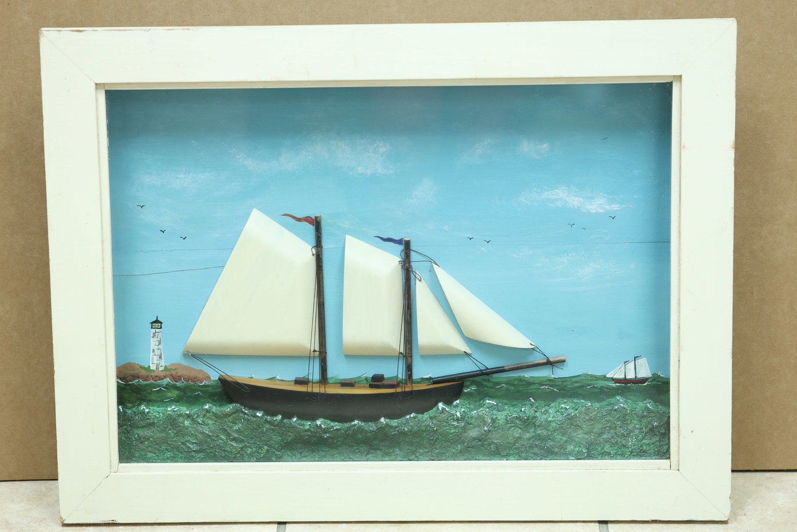 Jen Rice Schooner and Lighthouse Mixed Media Shadow Box: Framed mixed media relief depicting a two masted schooner near a lighthouse with layered textured elements. The reverse is marked Jen Rice 4 13. The direct forms and narrative presentation relate to f