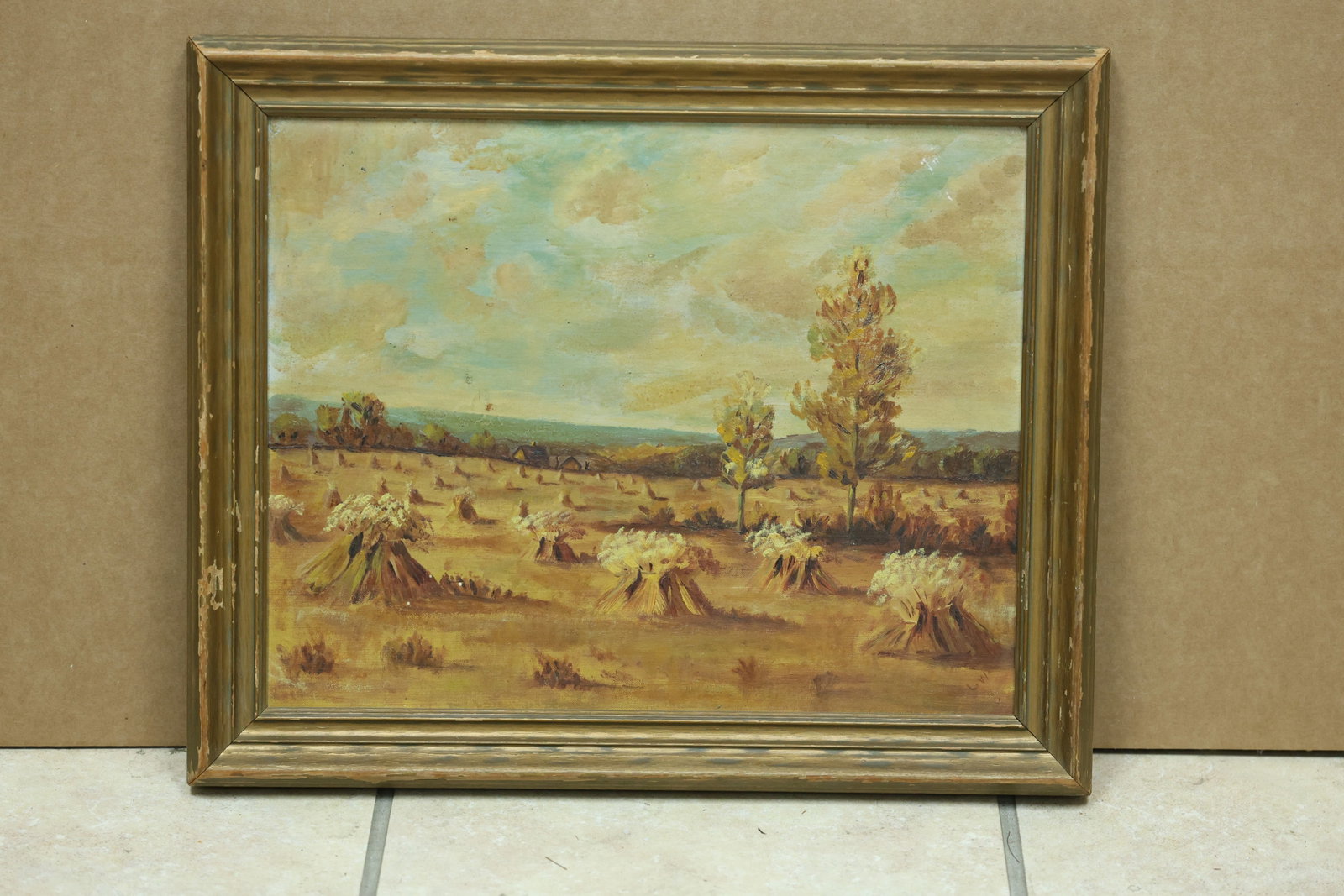 LW Initialed Autumn in the Foothills Landscape Painting: Framed rural landscape painting depicting workers and harvested fields beneath distant hills. The reverse is marked Autumn in the Foothills and the work bears the initials LW. The composed view relate