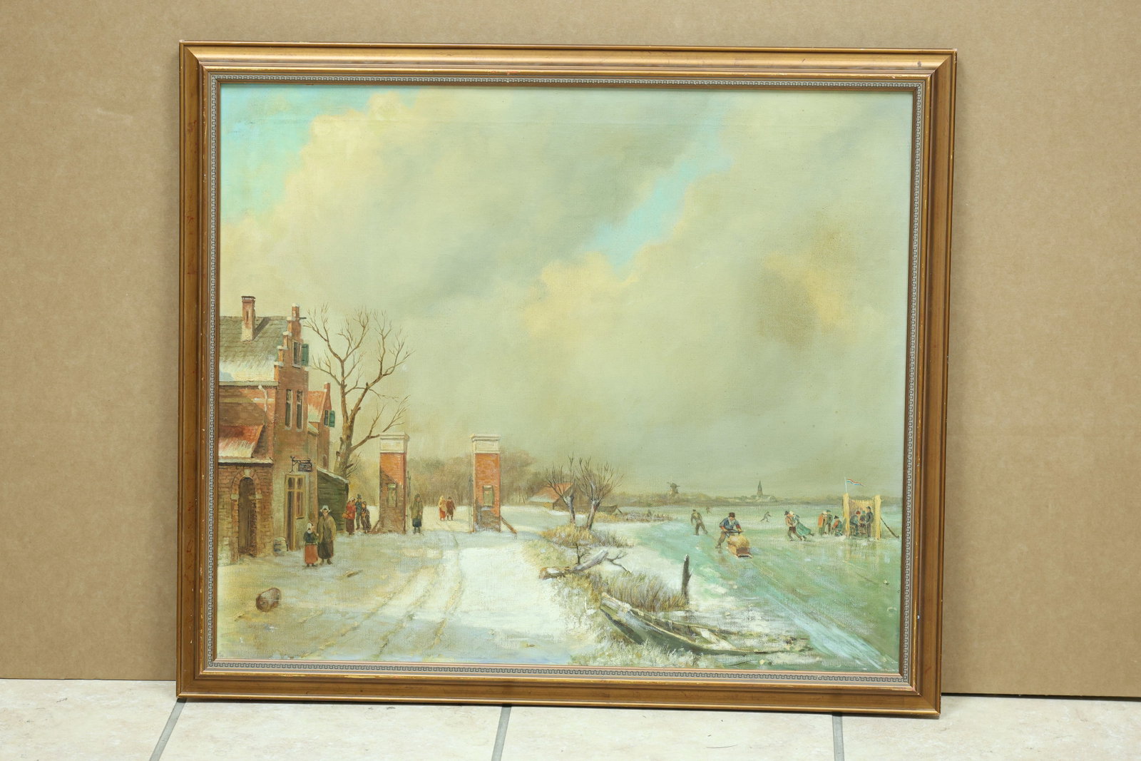 Dutch Style Winter Skating Canal Landscape Painting: Framed winter landscape painting depicting figures skating on a frozen canal or pond near houses and trees. No readable artist signature is visible in the reviewed photographs. The composed view relat