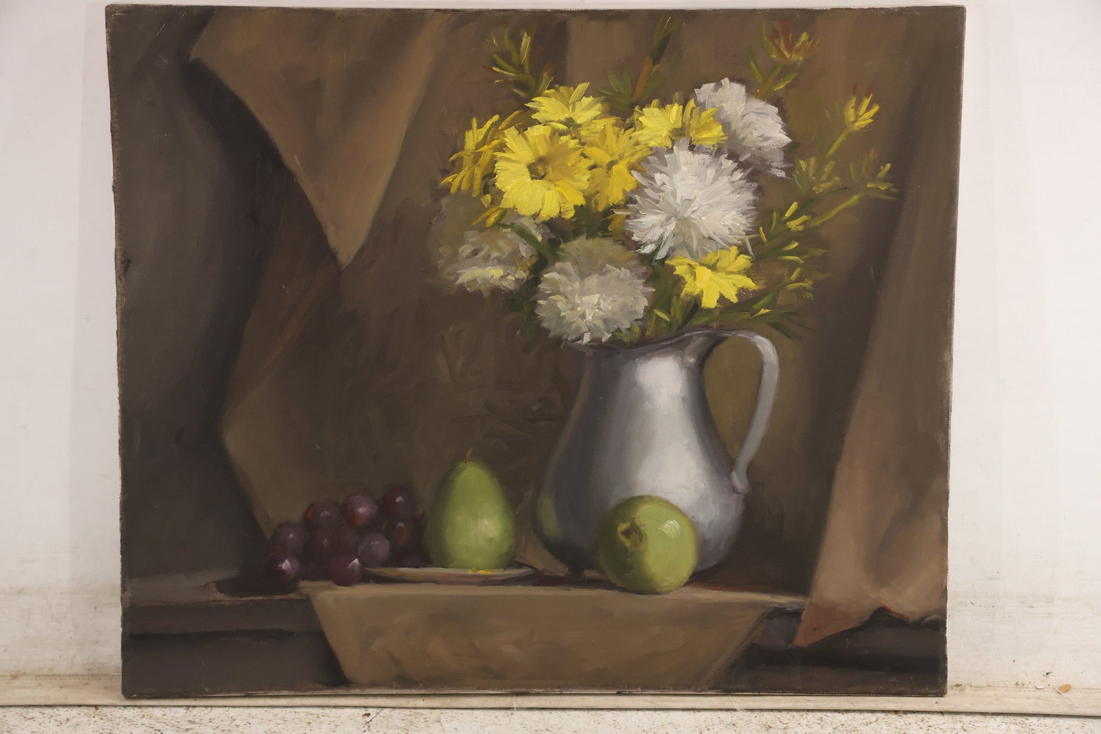 Signed Dee Kersting Floral Still Life Oil Painting 2006: Original floral still life painting on canvas signed Dee Kersting on the back and dated 4 06. Yellow and white flowers rise from a metal pitcher beside fruit and draped fabric. The controlled
