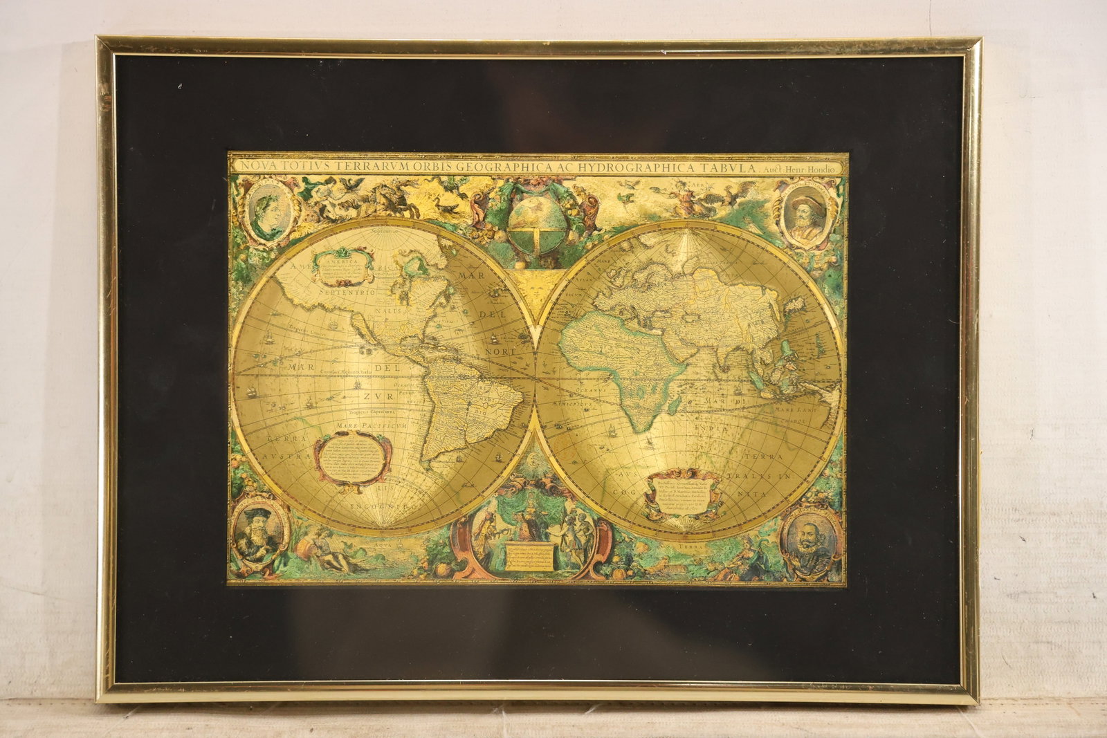 Manifestations Vintage Holographic World Map Foil Print: Vintage etched metallic foil world map print with a photographed Manifestations label on the back. The framed image uses reflective gold tone surfaces and optical line patterns to create a shifting di