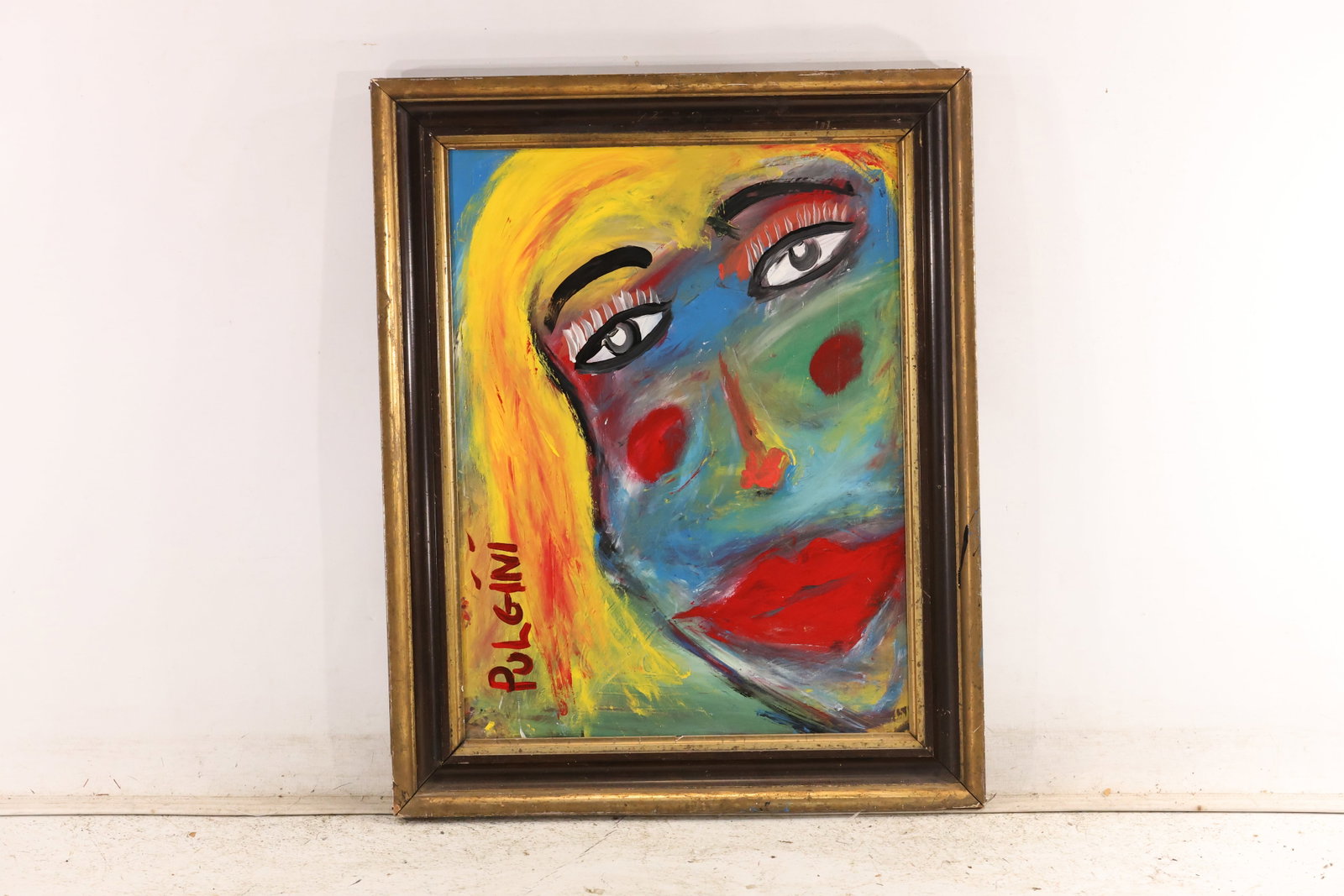 Signed Tom Pulgini Colorful Female Face Oil Painting: Signed Tom Pulgini oil painting on board depicting a close female face with yellow hair red lips and layered green blue pink and orange passages. The work uses simplified forms strong black contours a