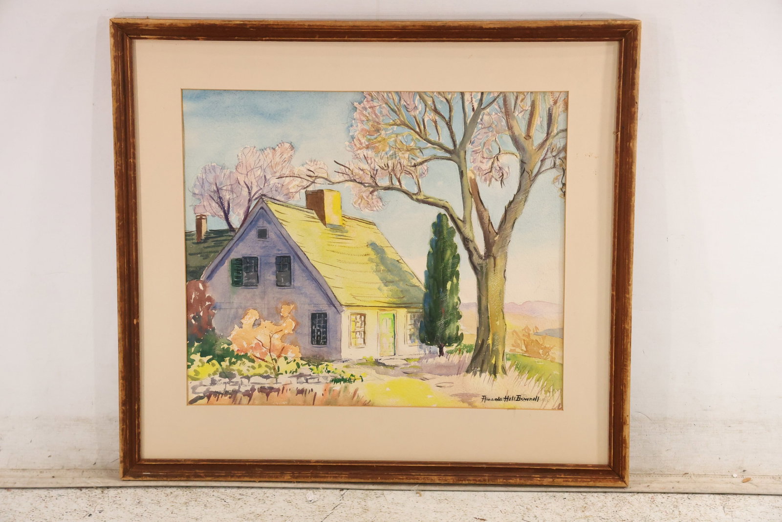 Signed Amanda Hall Brownell Connecticut Landscape Watercolor: Original watercolor on paper signed Amanda Hall Brownell. The spring landscape shows a gray cottage beneath flowering trees with fresh green and yellow foliage, distant hills, and loose transparent co