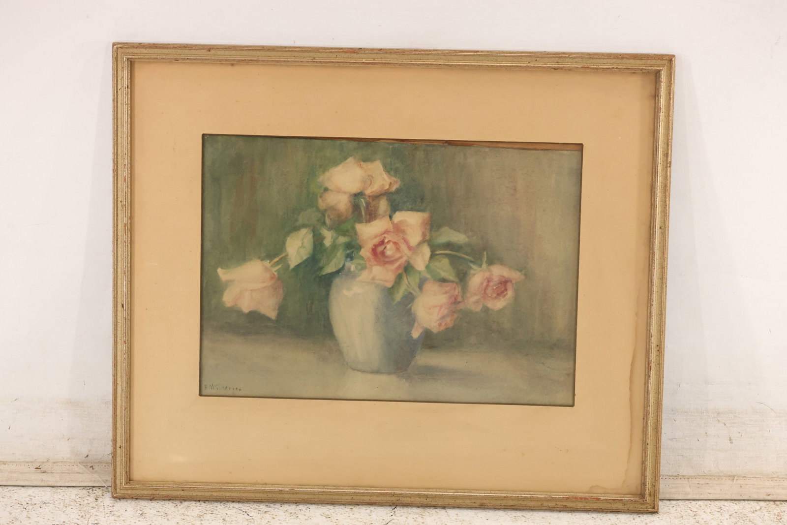Signed Floral Watercolor, Roses in Blue Vase, 1942: Watercolor on paper depicting pale pink roses in a blue vase. Signed lower left and dated 1942. Matted under glass in a wood and gold-toned frame. Artwork measures 10.5 x 15 inches. Outside frame meas