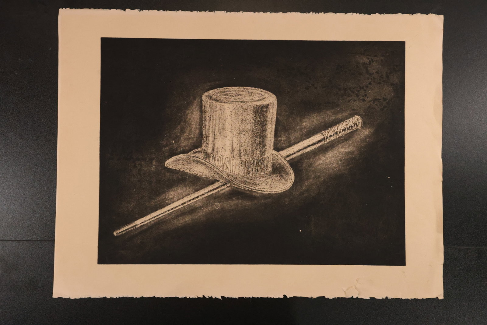 Magician’s Top Hat and Wand Print on Dark Ground: Black-and-white print depicting a top hat and wand, rendered with fine light marks against a dark textured background. Size: 22 x 30 inches. Shelf ID: mc1 **Pickup Notice:** This item requires a confi