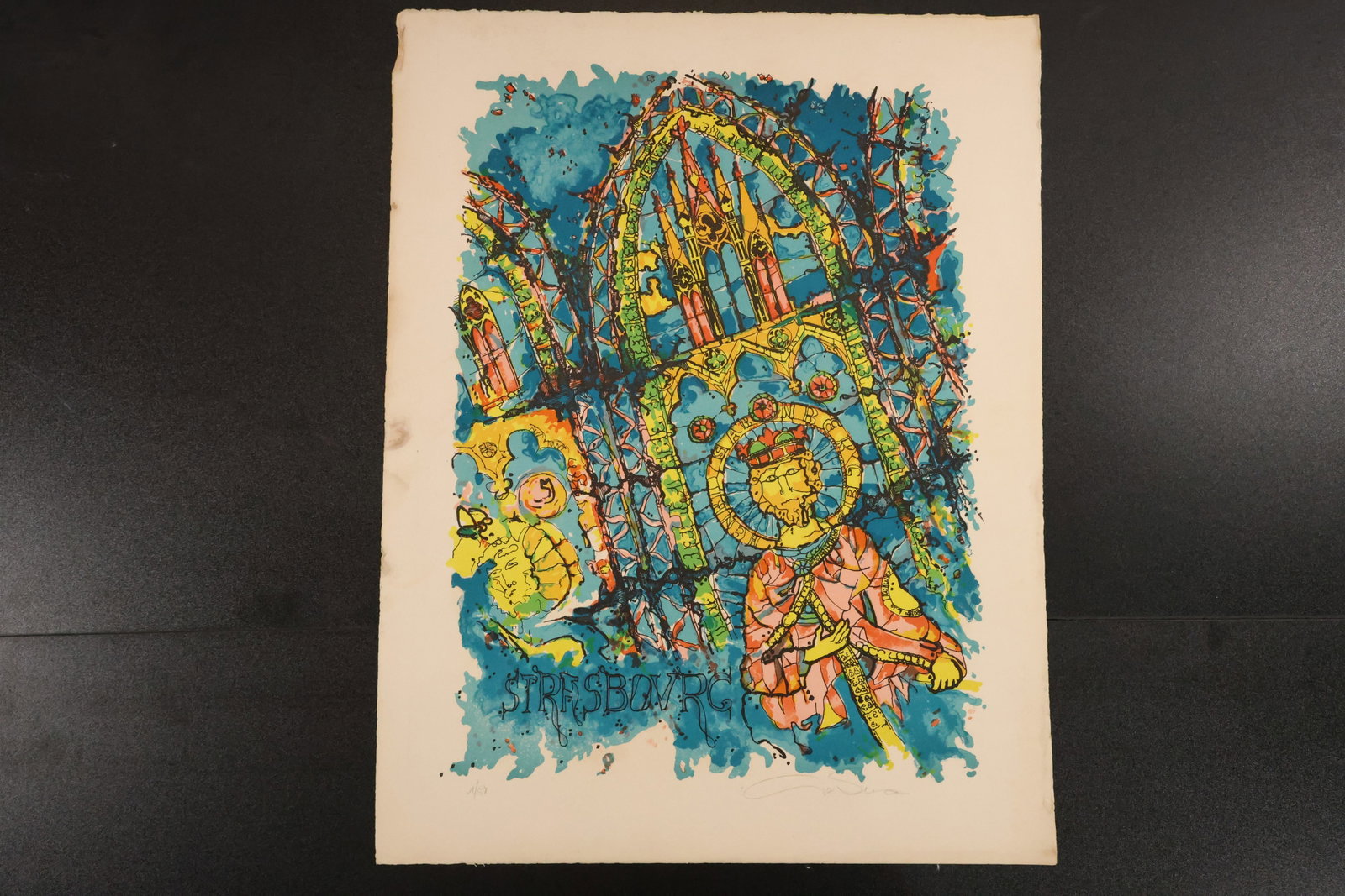 Signed “Strasbourg?? Cathedral Color Print: Color print with layered Gothic architectural forms and decorative figures in blue, turquoise, yellow, and orange. Includes the word “Strasbourg” and a signature at lower right. Size: 26 x 20 