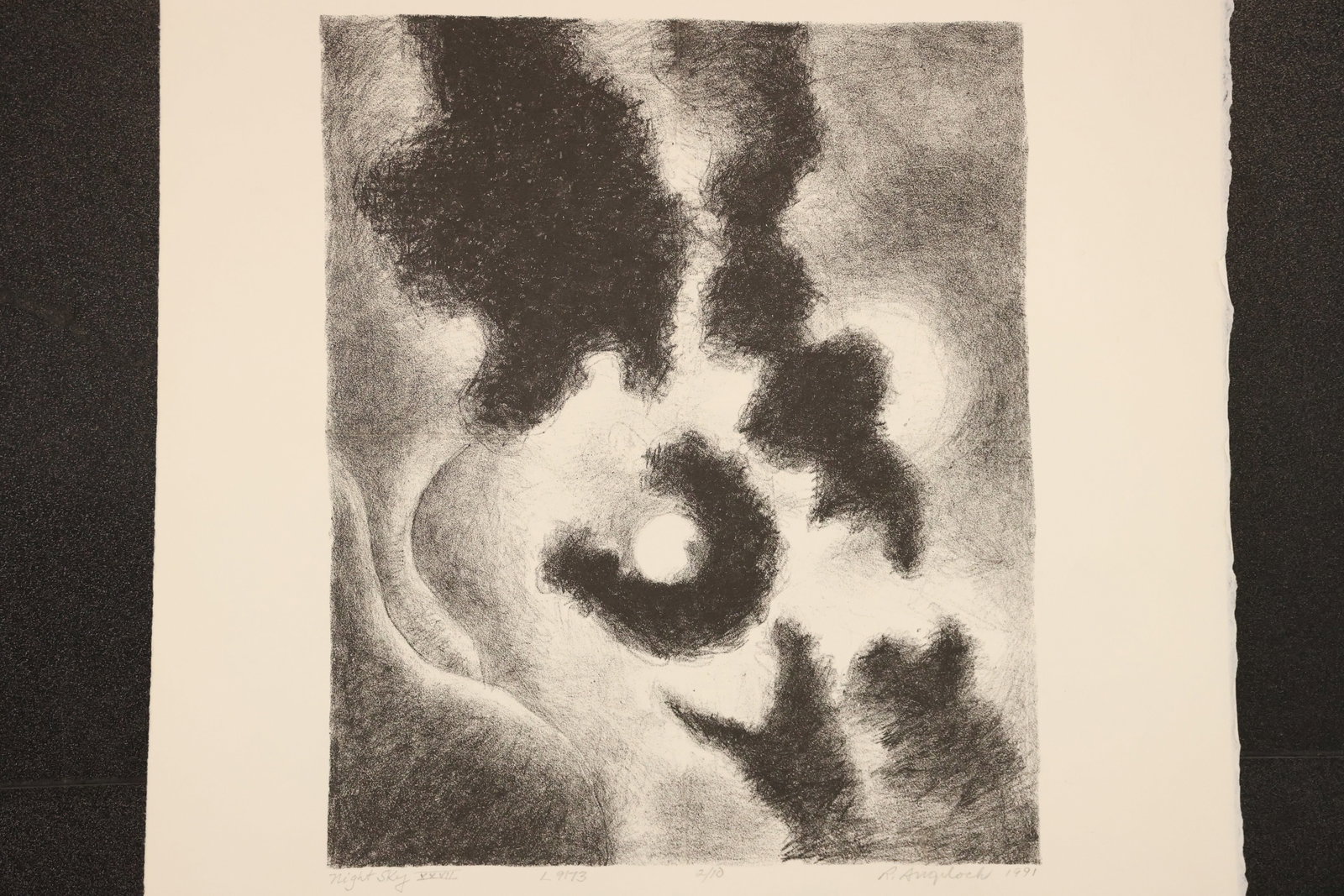 R. Angeloch Moon and Clouds Black and White Print: A black and white print by R. Angeloch depicting a pale moon surrounded by dark, swirling cloud forms. Soft tonal shading gives the sky a dramatic, atmospheric quality. Size: 13 x 17 inches. Shelf ID: