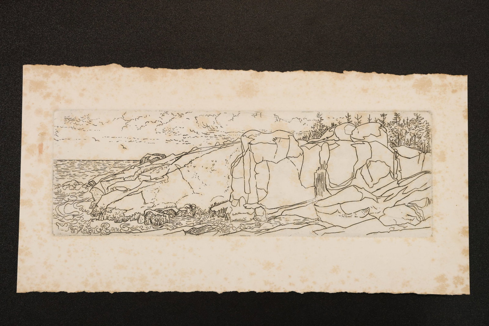 R. Angeloch Rocky Shore Line Drawing: A line drawing by R. Angeloch depicting an extended rocky shoreline. Fine dark contours describe uneven ledges, scattered stones, and the distant coast on a narrow horizontal sheet. Size: 7 x 14 inche