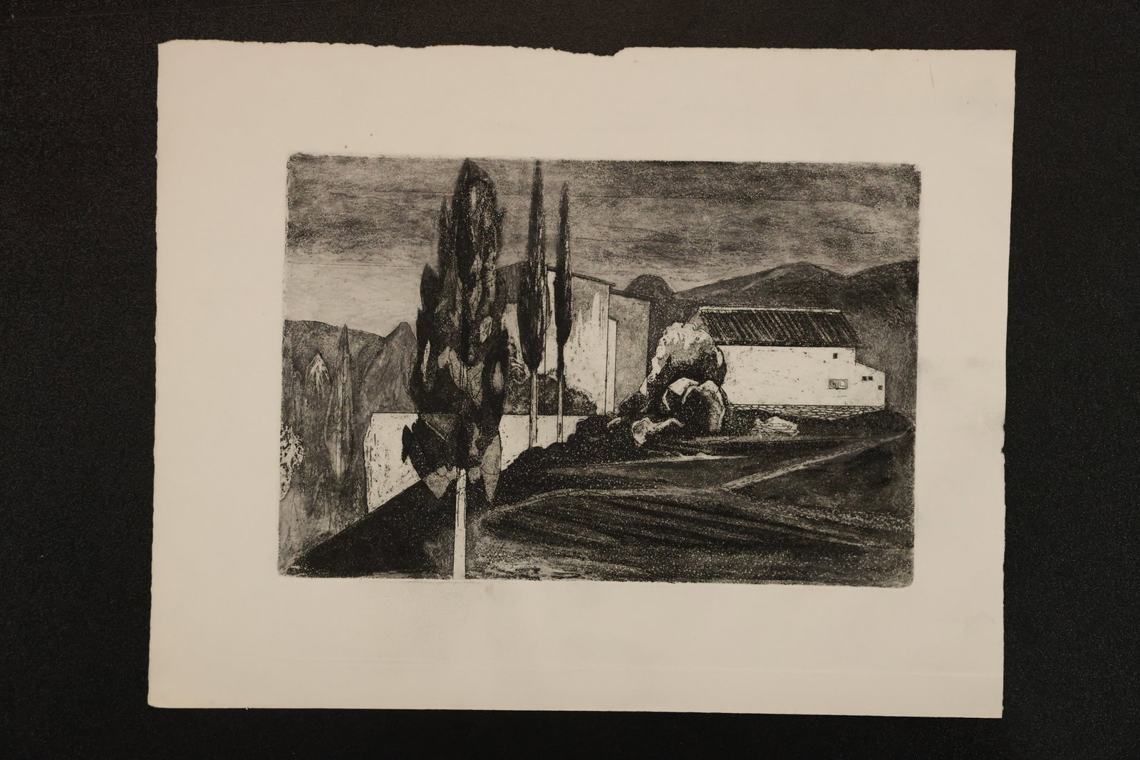 R. Angeloch Cypress Trees and Buildings Black and White Print: A black and white print by R. Angeloch depicting tall slender trees beside pale buildings. Strong shading defines the sloping foreground and distant hills. Size: 10 x 13 inches. Shelf ID: mc4 **Pickup