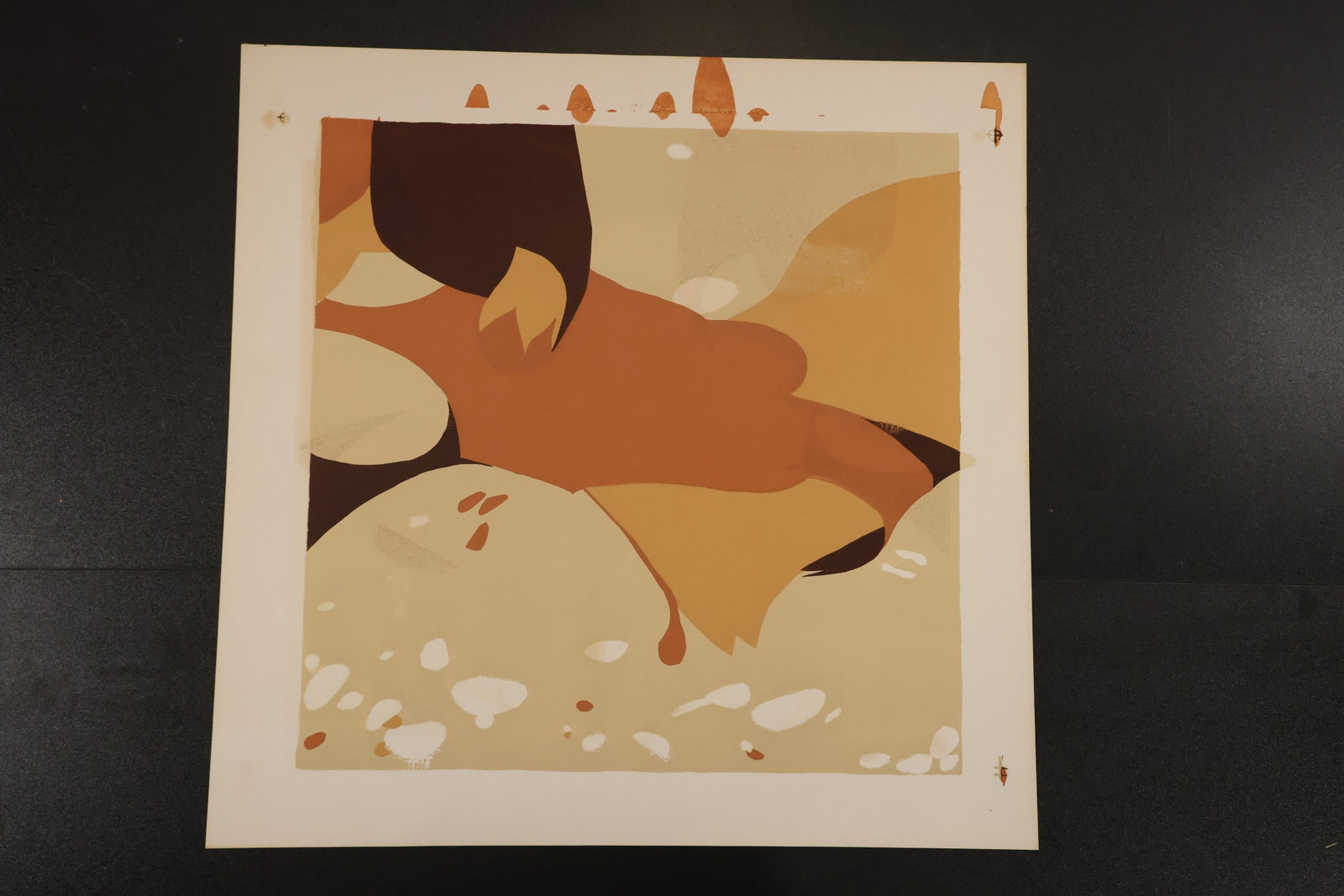 R. Angeloch Earth Tone Abstract Color Print: An unsigned color print attributed to R. Angeloch by the estate. Interlocking brown, orange, ocher, and cream shapes form an abstract composition with scattered pale accents. Size: 22 x 22 inches. She