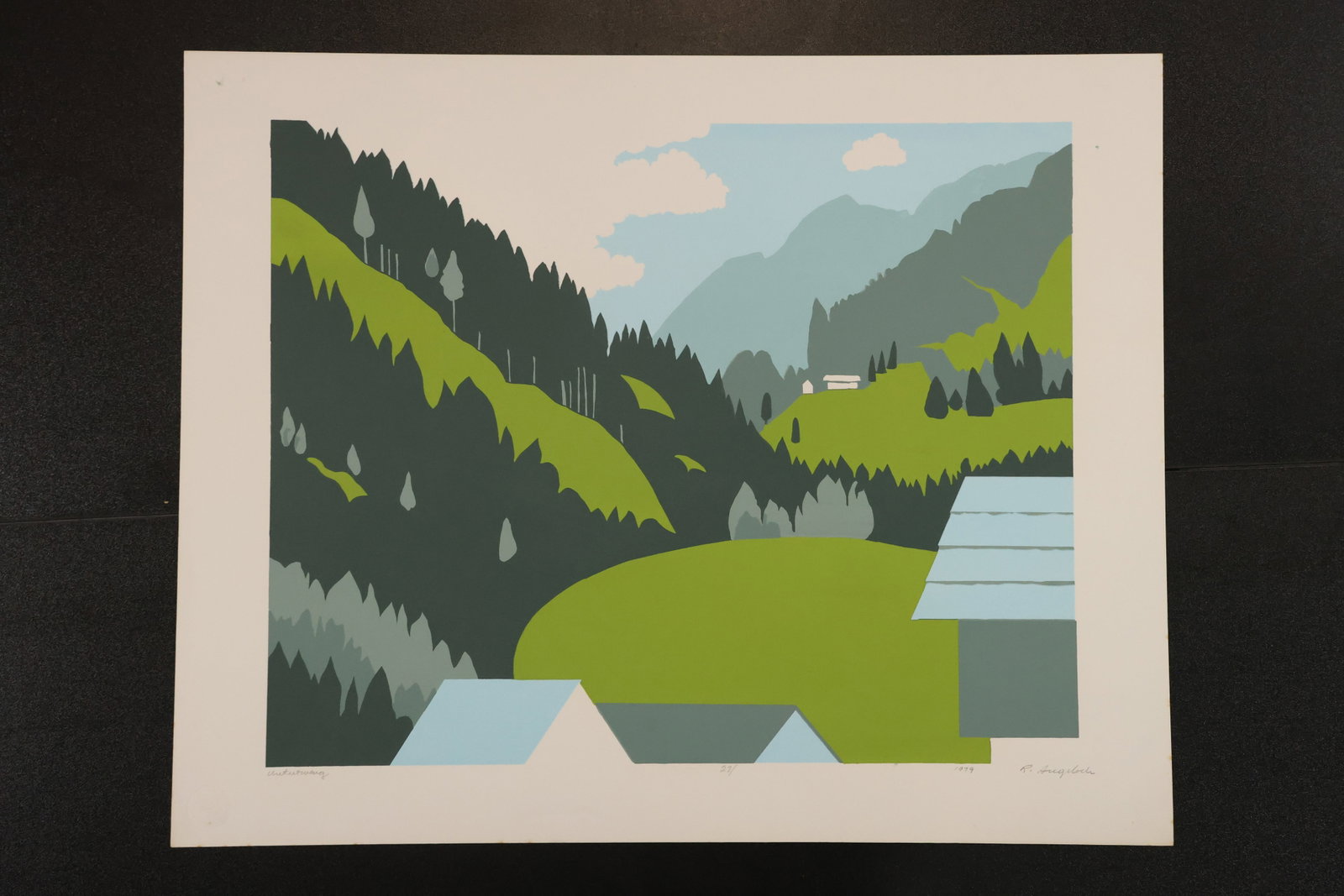 R. Angeloch Mountain Village Color Print: A color print by R. Angeloch depicting green hills, dark evergreens, and small buildings within a mountain valley. Blue-gray peaks and pale clouds rise in the background. Size: 16 x 20 inches. Shelf I